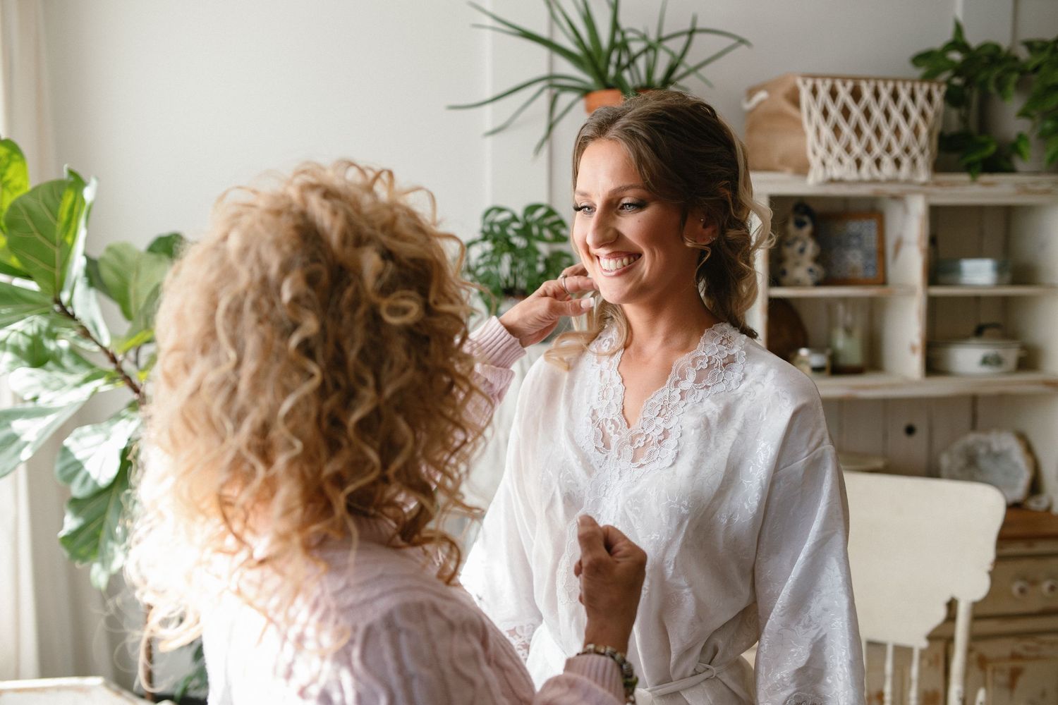 Two people sharing a joyful moment in bright, plant-filled room.