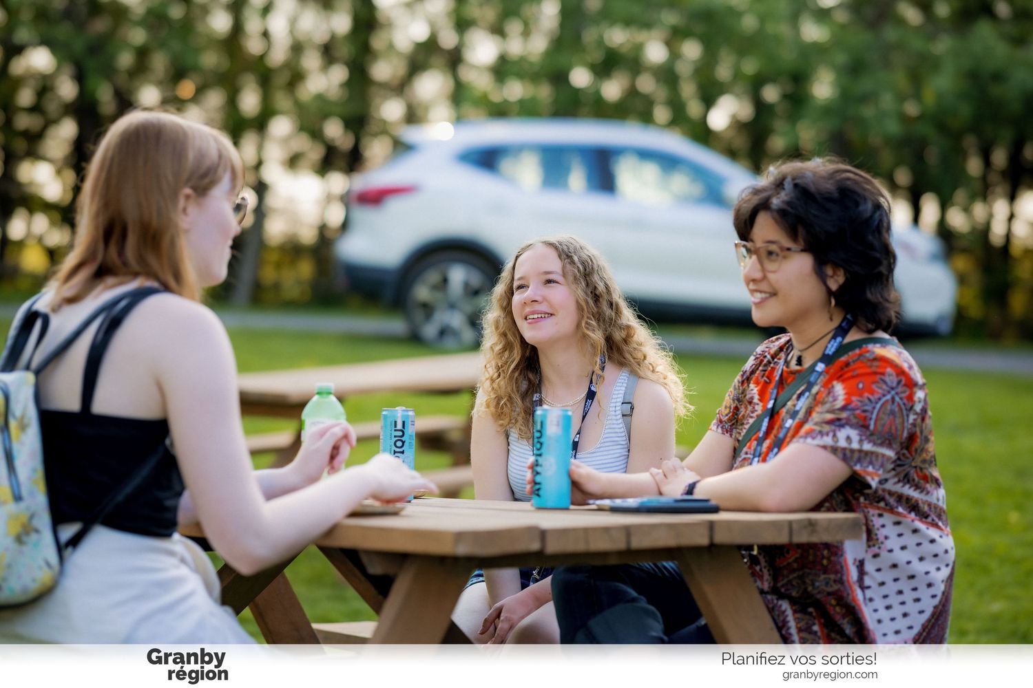 Friends gathered around outdoor tables enjoying conversation and drinks.