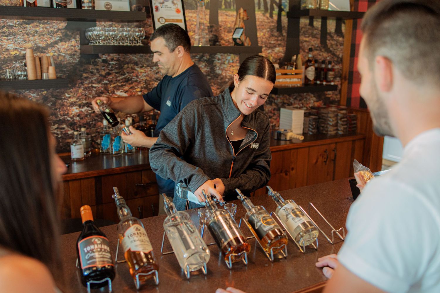 Warm-toned interior of a tasting room with guests at the bar counter.