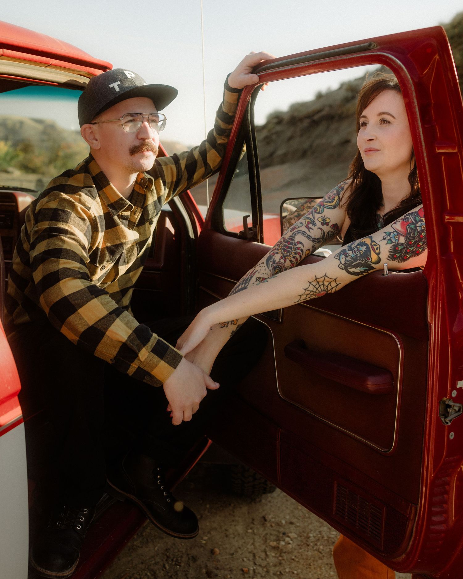 Romantic moments captured inside a classic red truck with desert mountains in background.