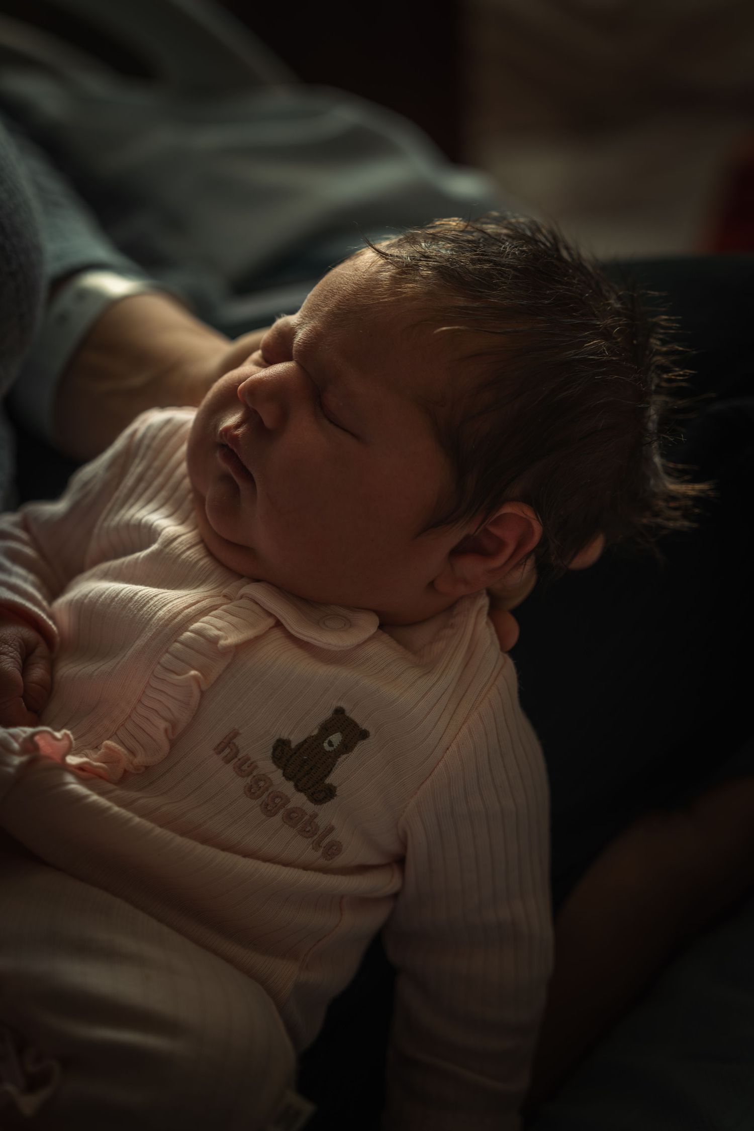Baby sleeping peacefully in a white onesie with a small animal print design.