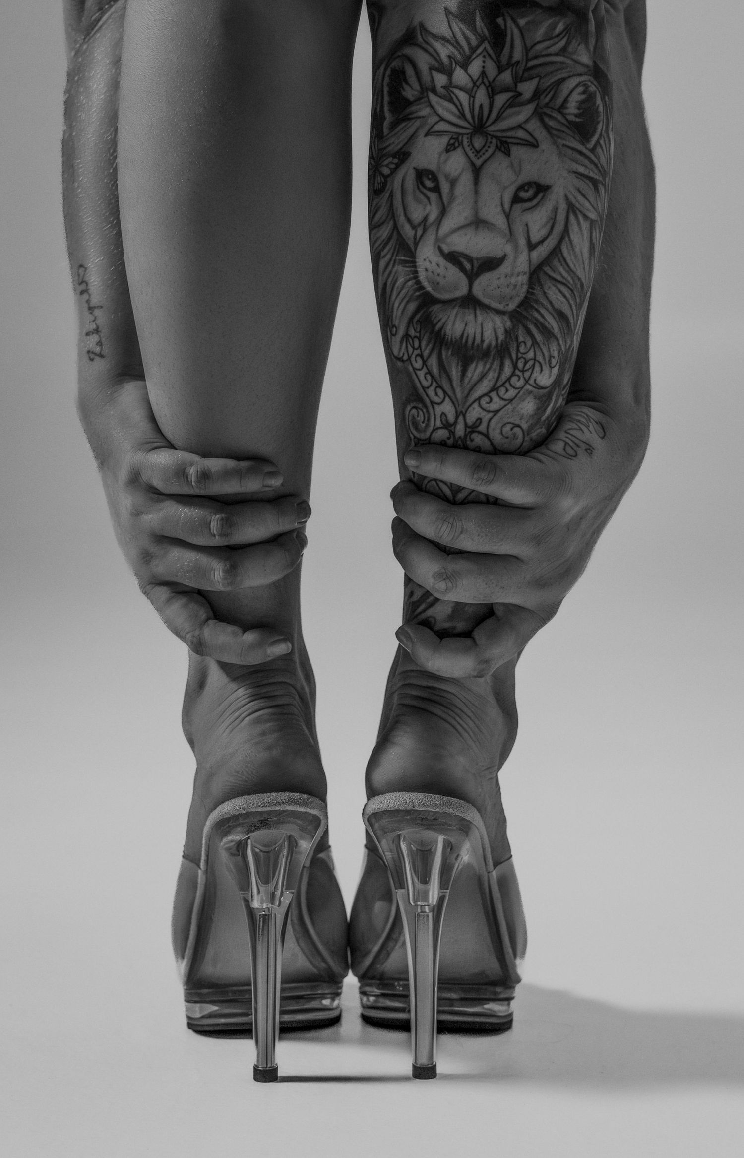 Close-up sequence showing legs with lion tattoos wearing different shoes from jeans to high heels in black and white.