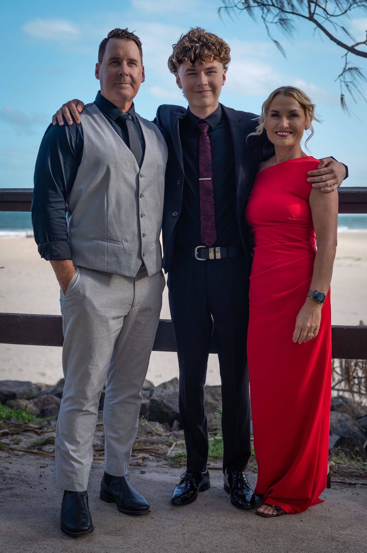 A formal gathering on a beach with people in elegant evening wear.