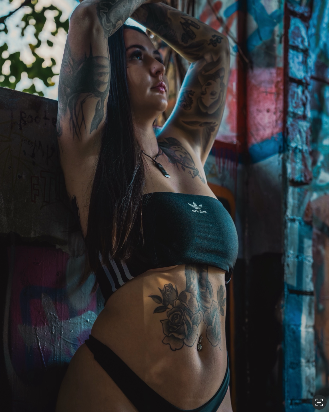 Moody portrait series showcasing tattoo art in an urban setting with graffiti walls.