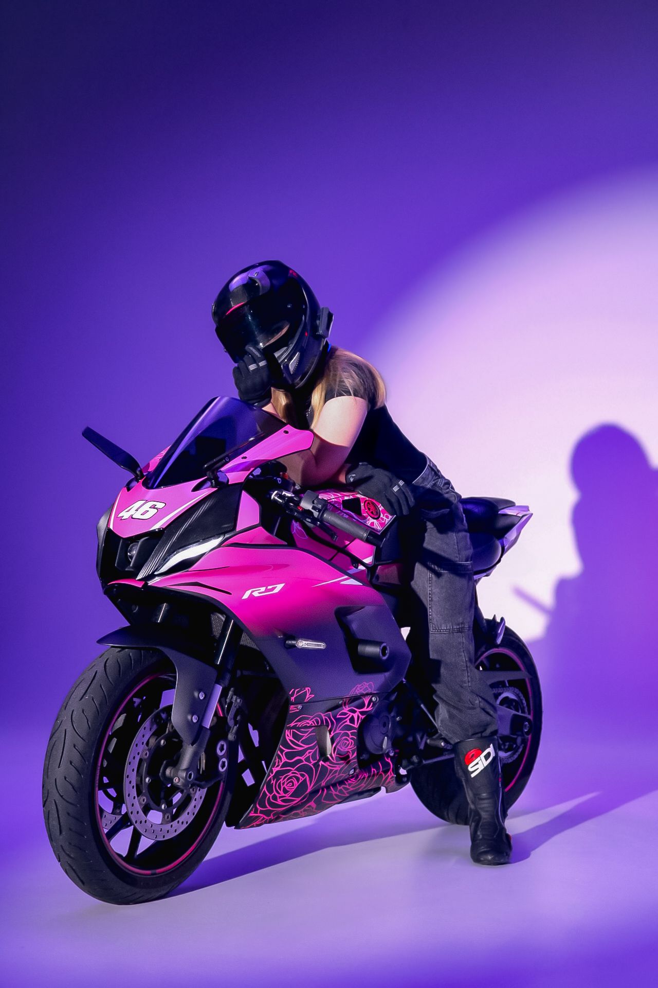 Pink sports motorcycle photographed against purple gradient background with dramatic lighting.