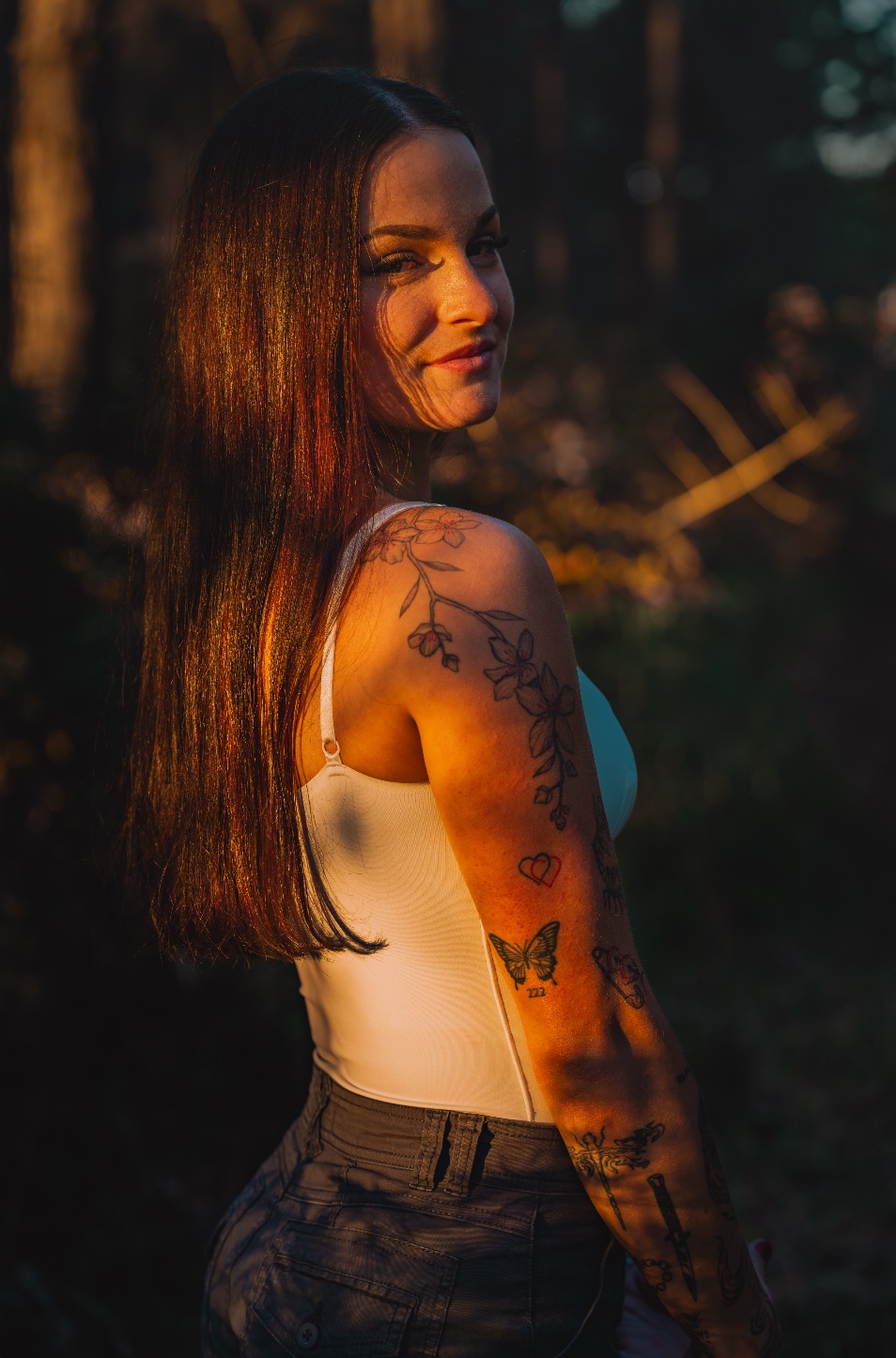 Sunset portrait series highlighting tattoo artwork and natural lighting in a forest setting.