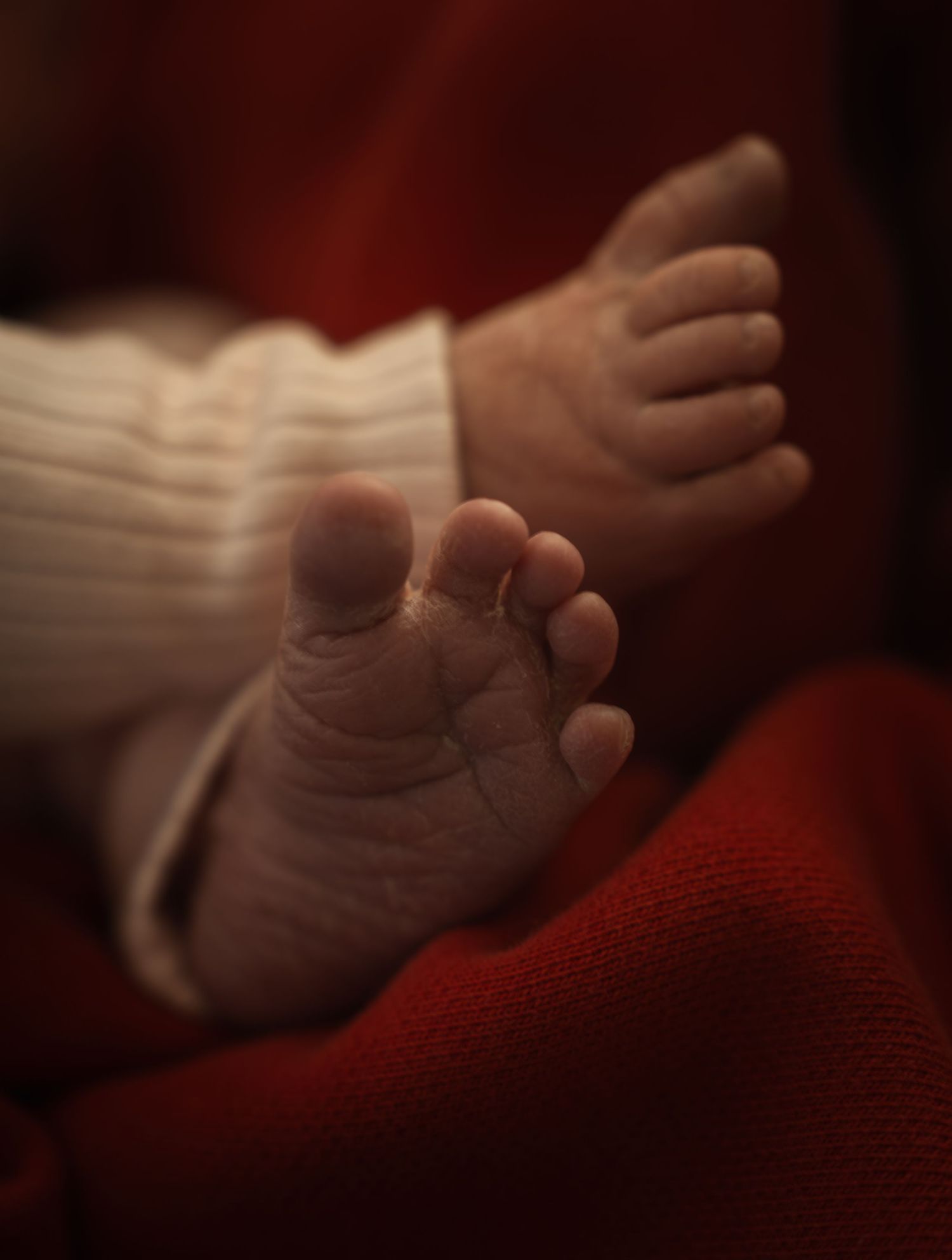 A series of close-up shots showing a baby's tiny hand grasping against a red and white background.