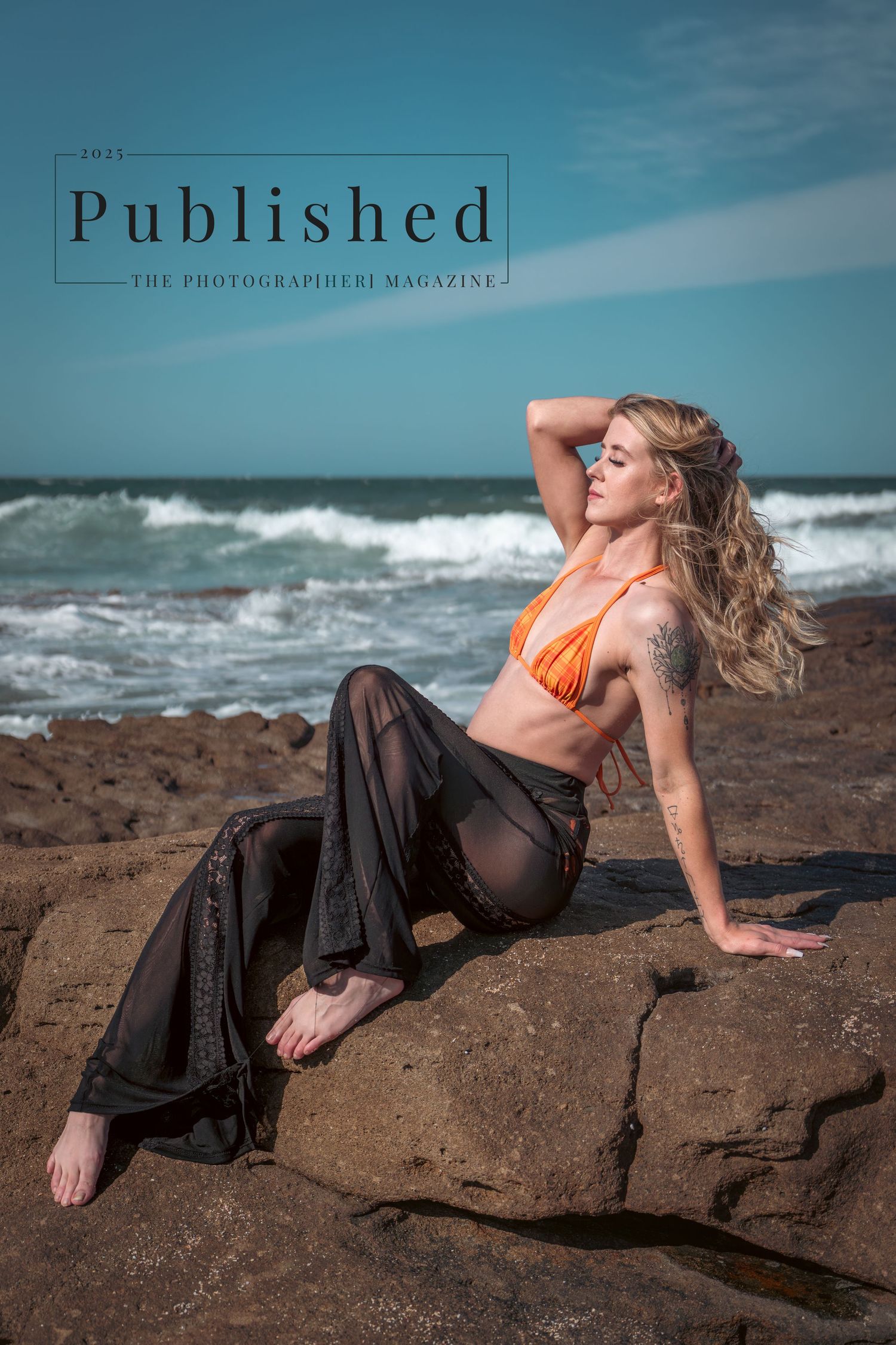 Beachwear fashion photo of model in orange bikini top and flowy pants posing on rocky shore with crashing waves.
