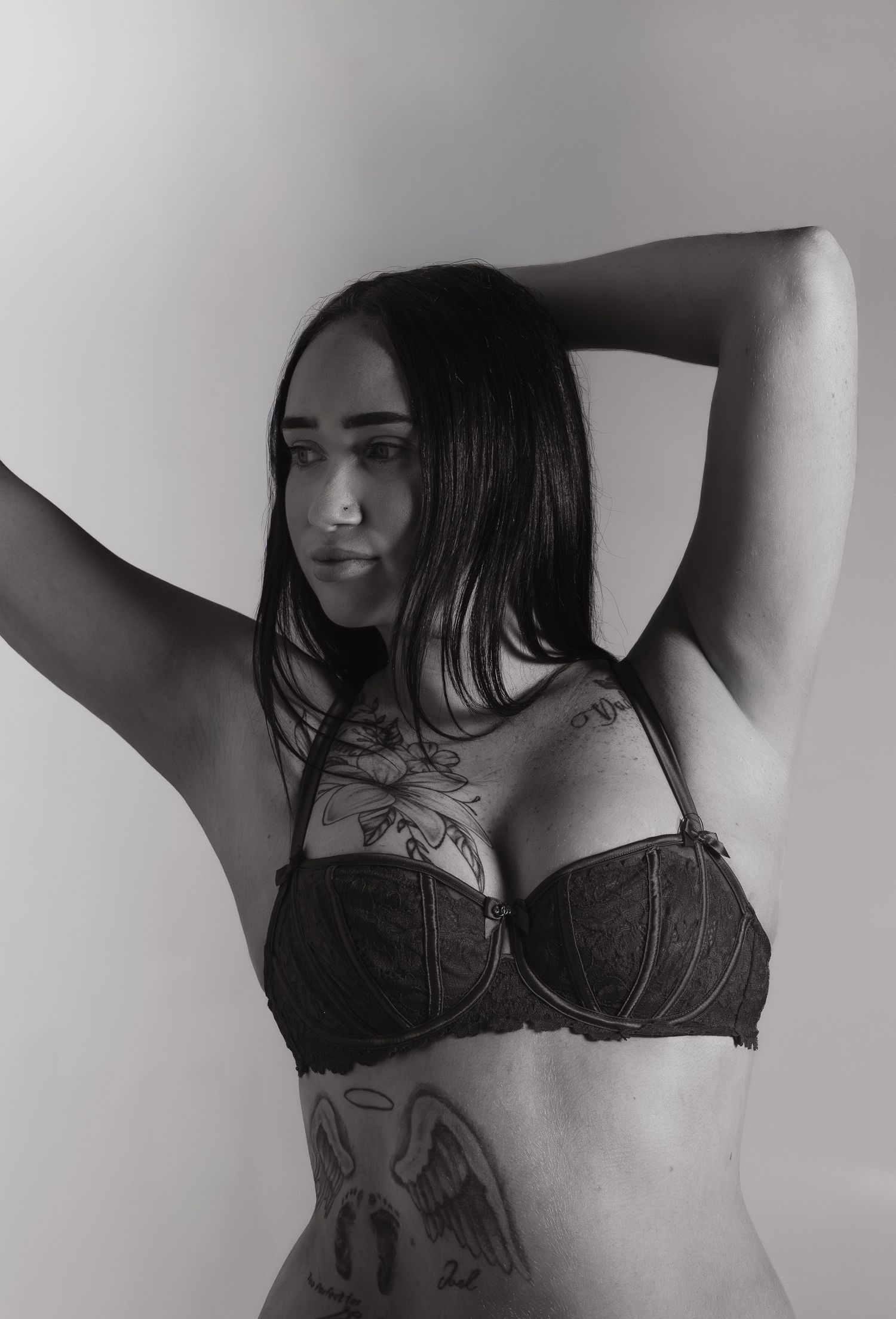 Black and white artistic boudoir photography series showing torso with tattoos and lingerie in minimalist style.