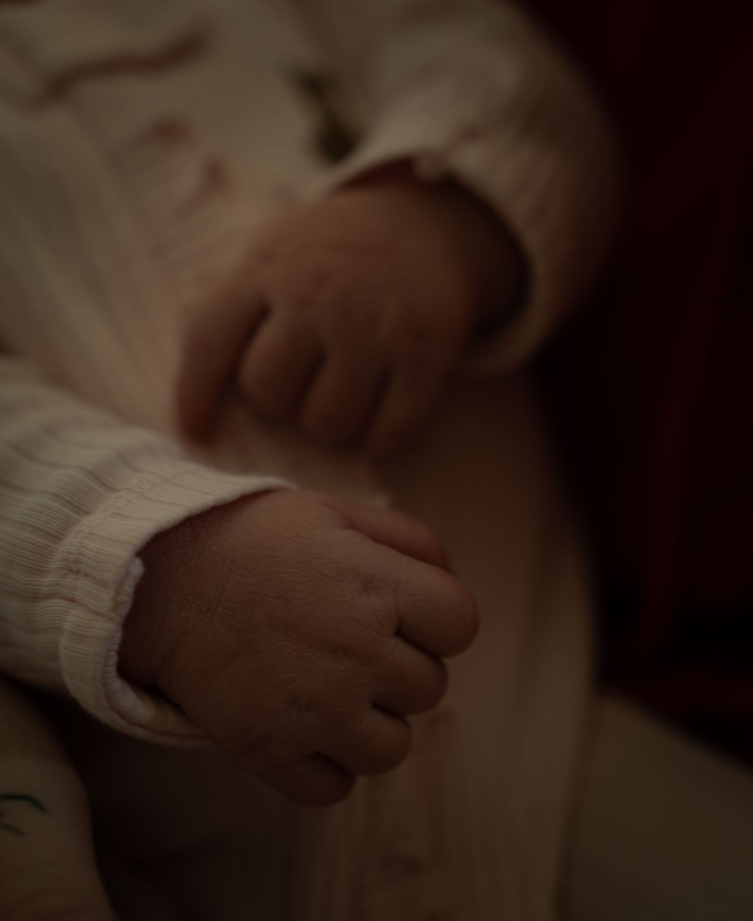 Close-up of hands gently touching in an intimate and emotional moment against a dark background.