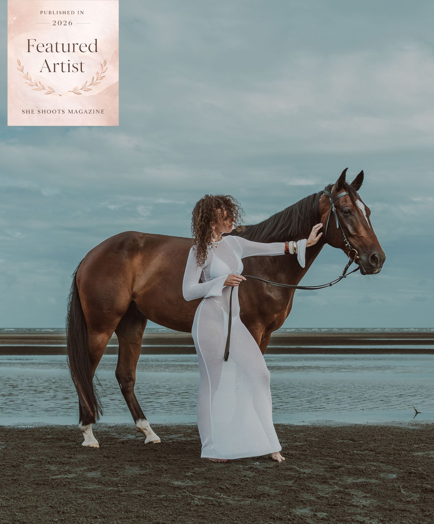 Woman in white gown poses with chestnut horse on beach, featured in She Shoots Magazine 2024.