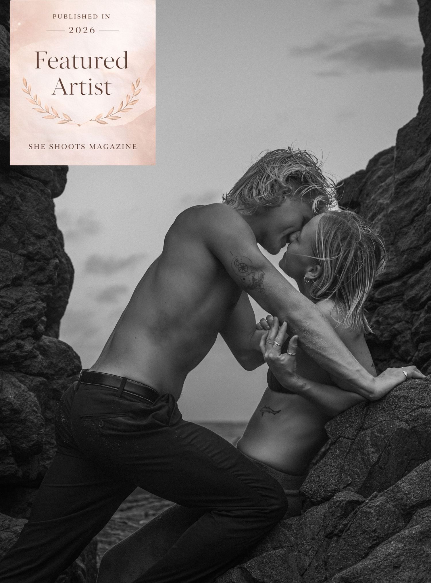 Black and white photo of a couple sharing an intimate moment among rocky cliffs, featured in She Shoots Magazine 2026.