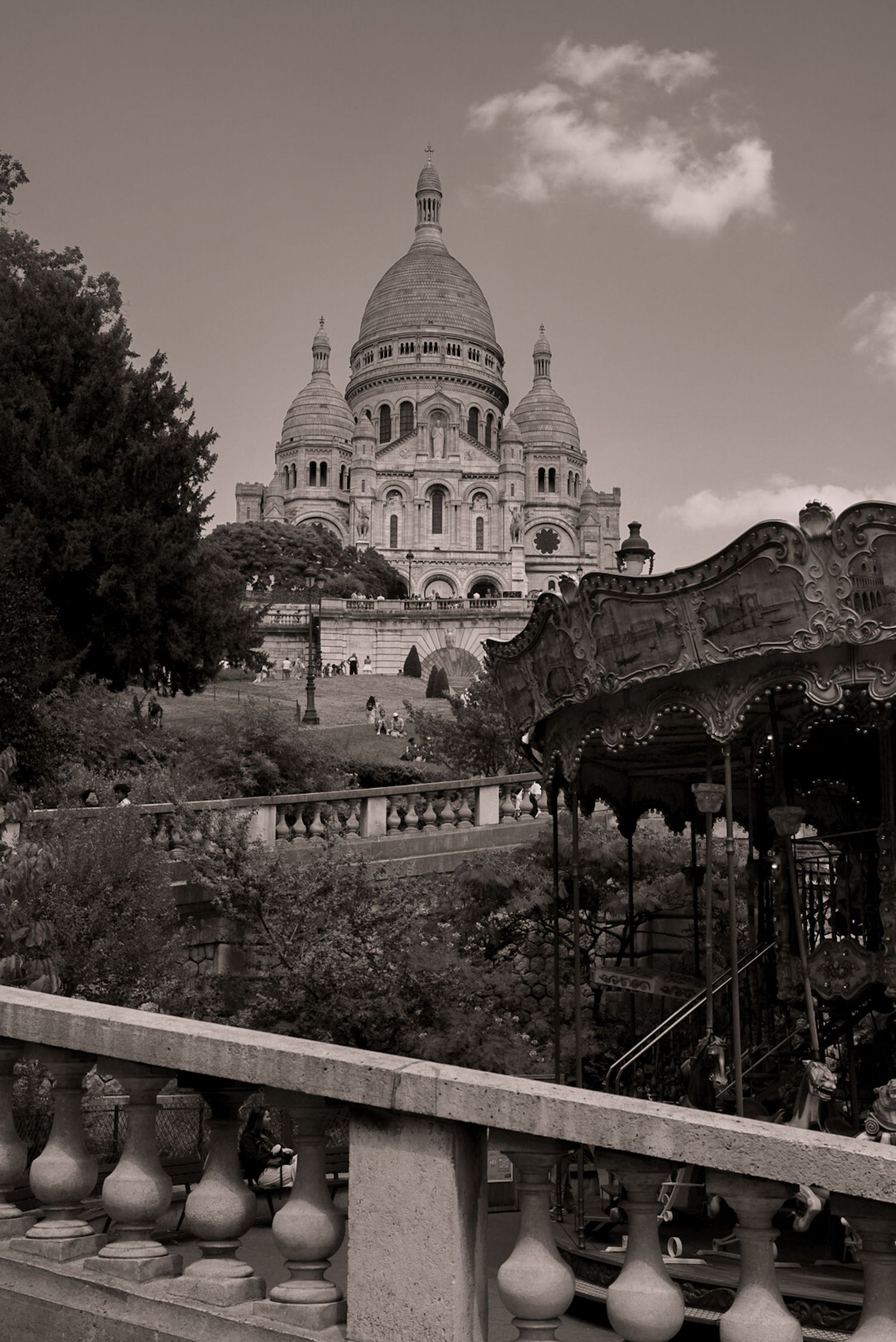 Black and white photo of Sacré-Cœur Basilica in Paris with a vintage carousel in the foreground.