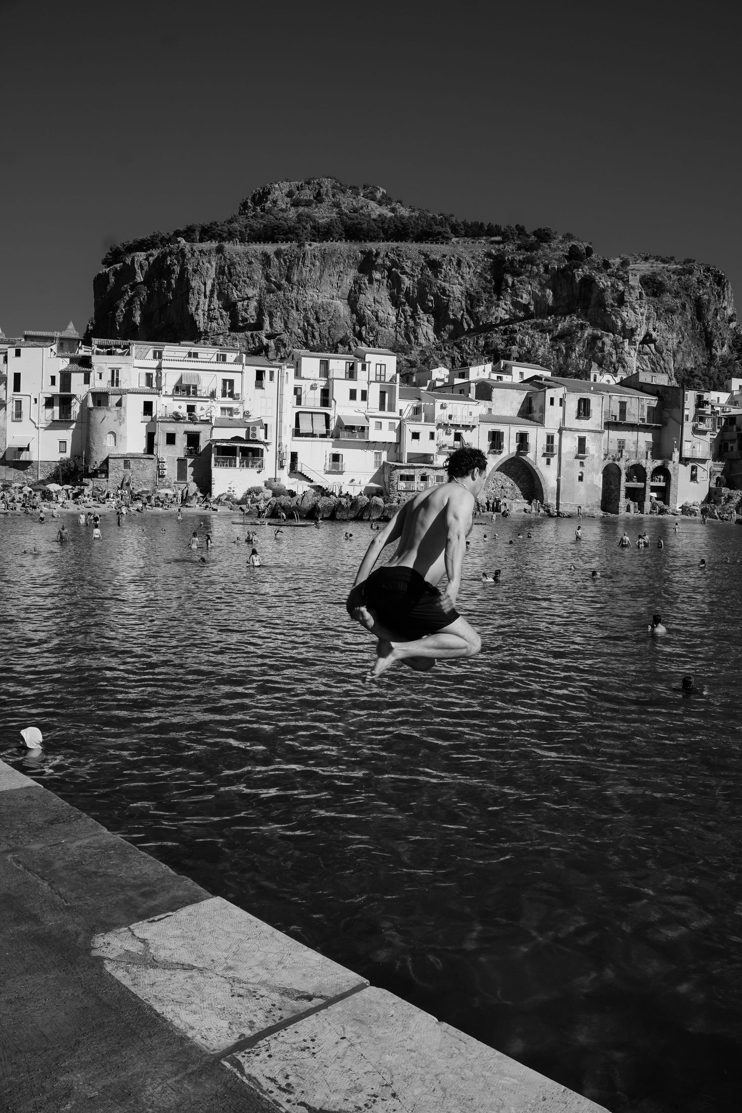 A scenic black and white view of waterfront houses along a Mediterranean coastline.