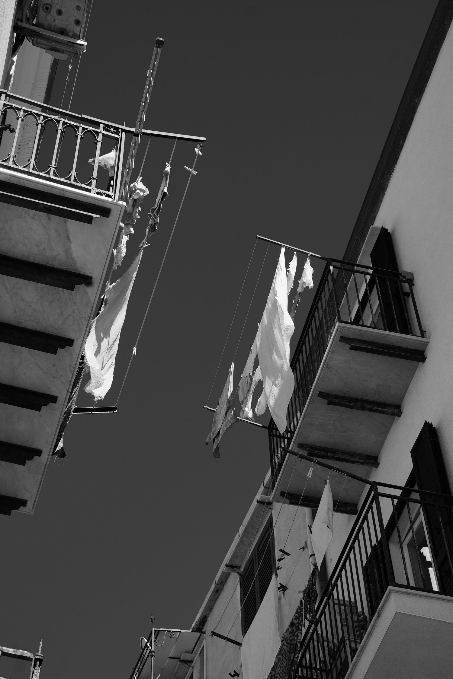 Hanging white laundry against dark building exterior with metal railings.