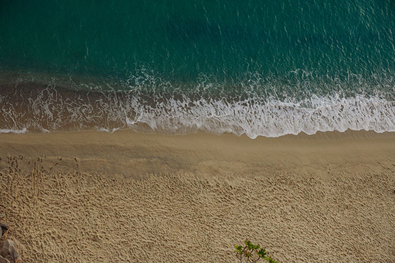 Aerial view of turquoise ocean waters meeting a sandy beach shoreline.