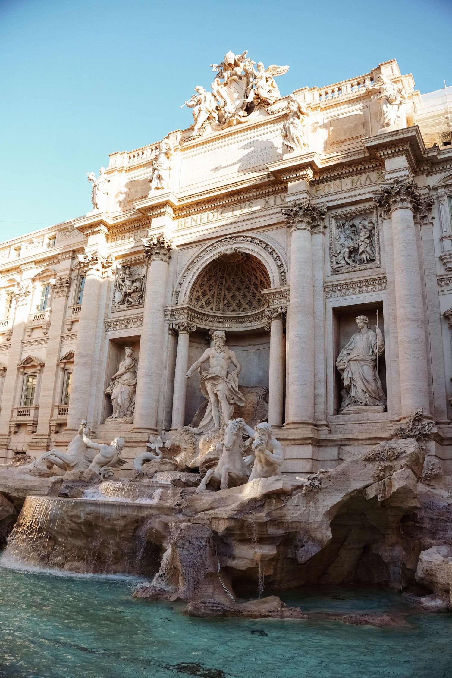 The iconic Trevi Fountain in Rome, Italy, featuring Baroque sculptures and turquoise water against a clear blue sky.