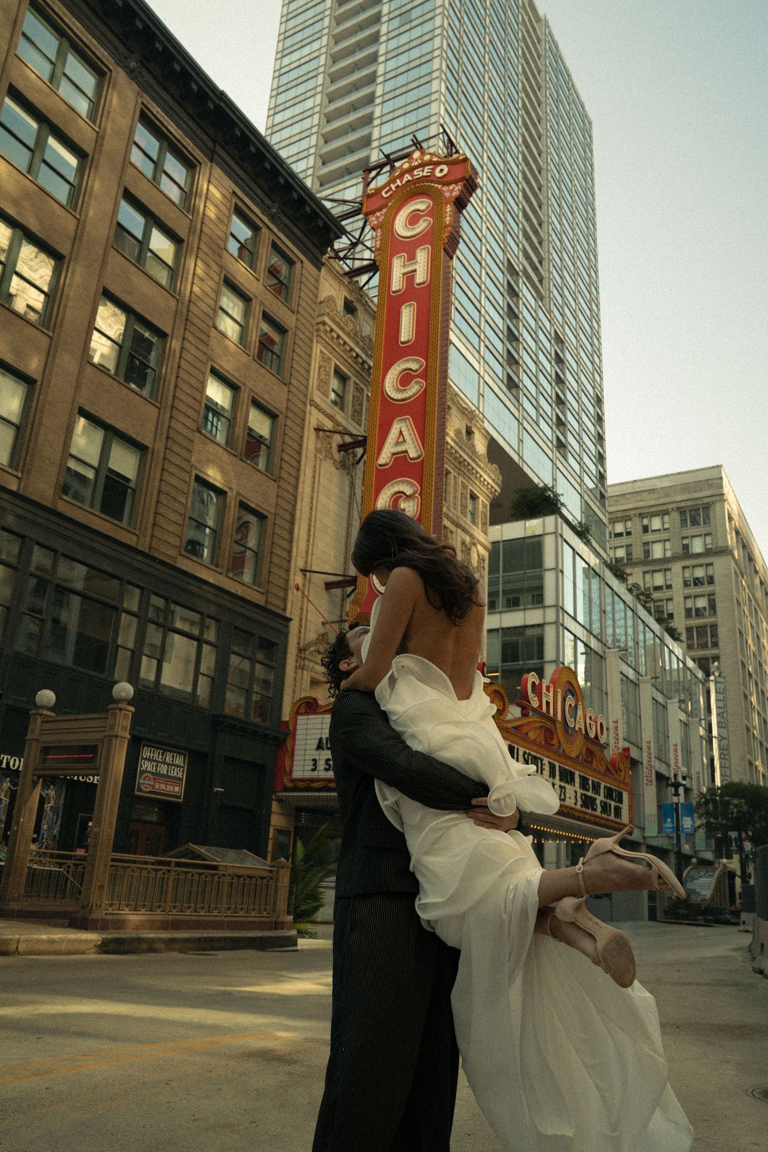 Couple sharing romantic embrace in front of iconic Chicago Theatre marquee sign on State Street.