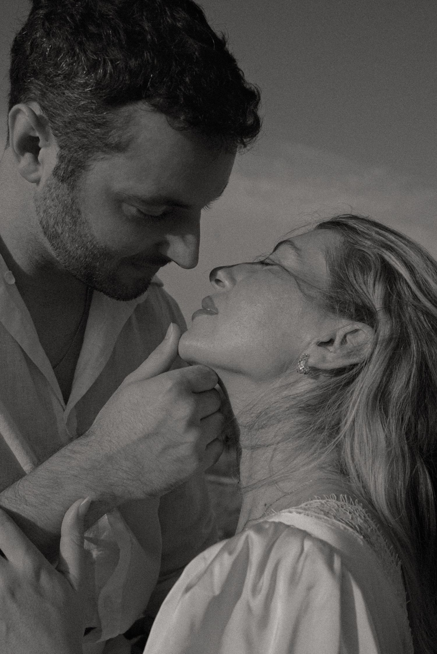 Black and white romantic couple portrait with man tenderly holding womans chin as they lean in close together.