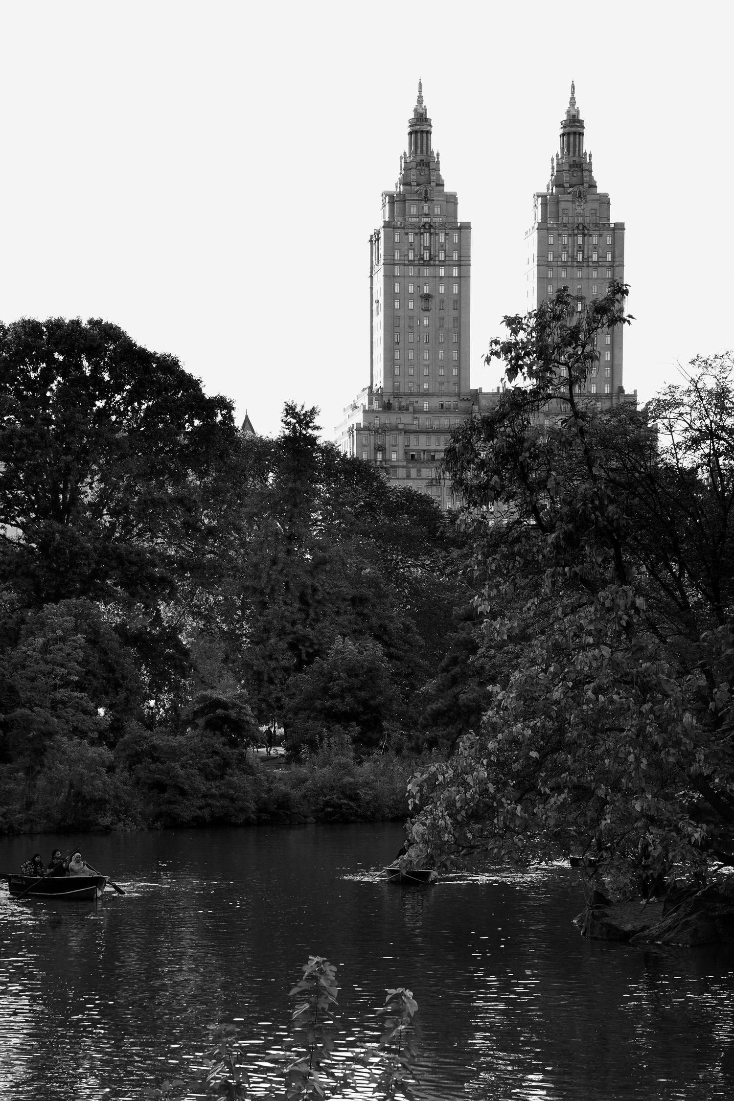 Twin towers of the San Remo building rising above Central Park trees in black and white.