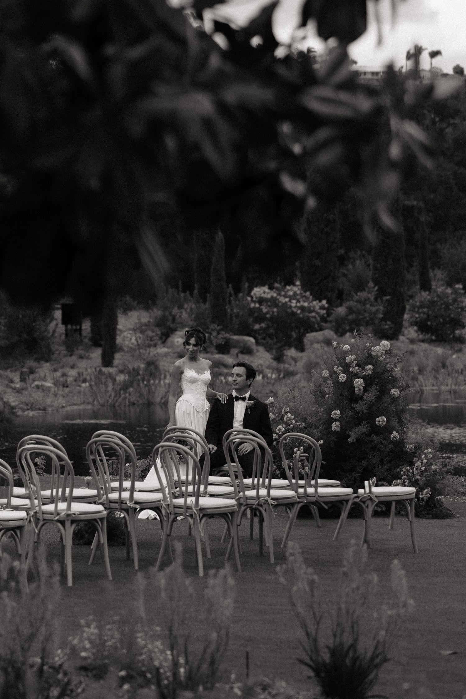 Bride and groom walking through an outdoor garden wedding ceremony venue in black and white.