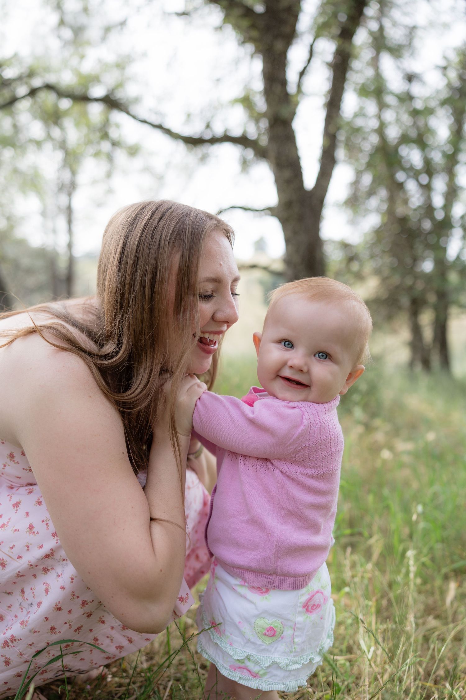 Mother and baby girl sharing a happy moment together in a lush green park.