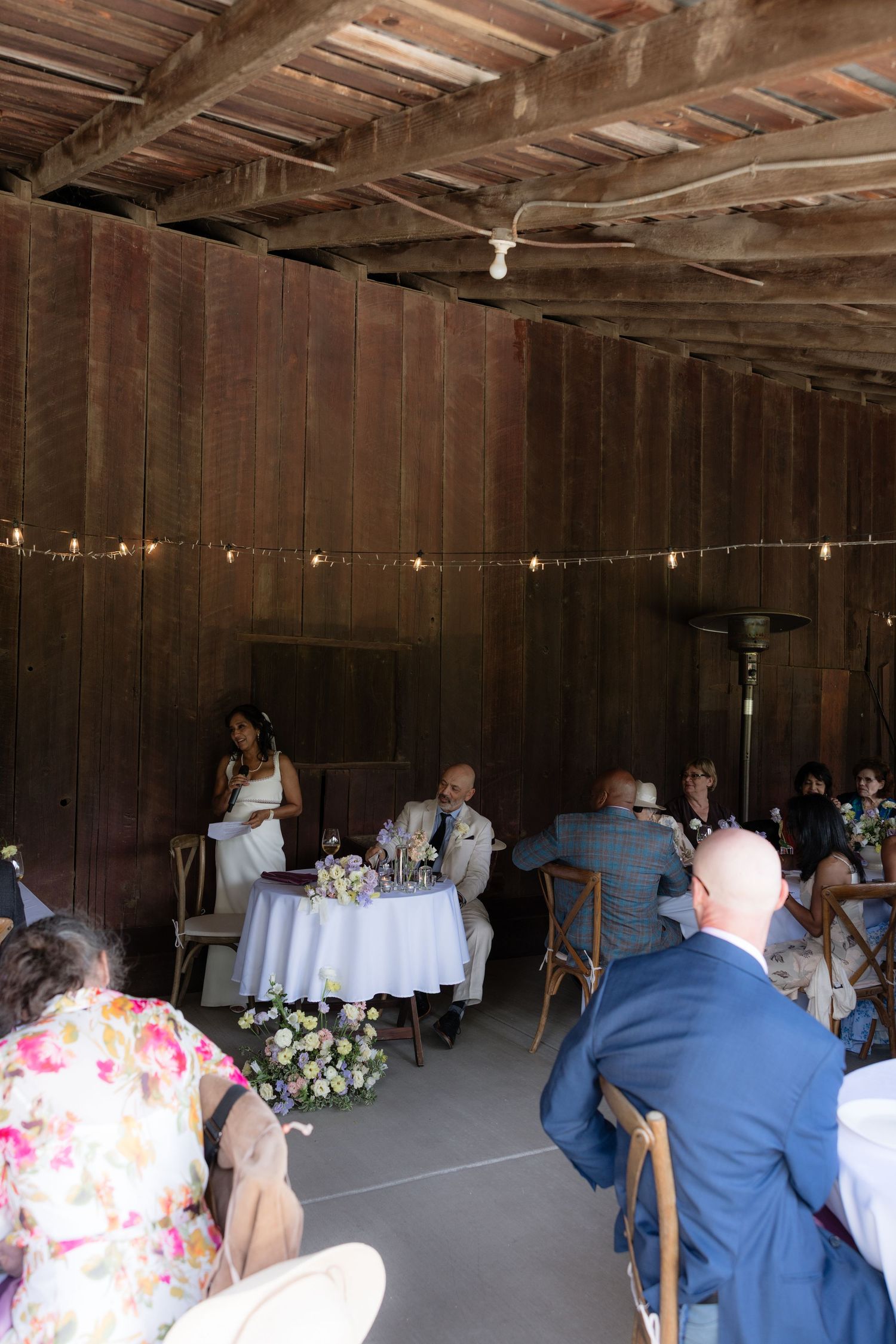 Intimate barn wedding reception with string lights and sweetheart table.