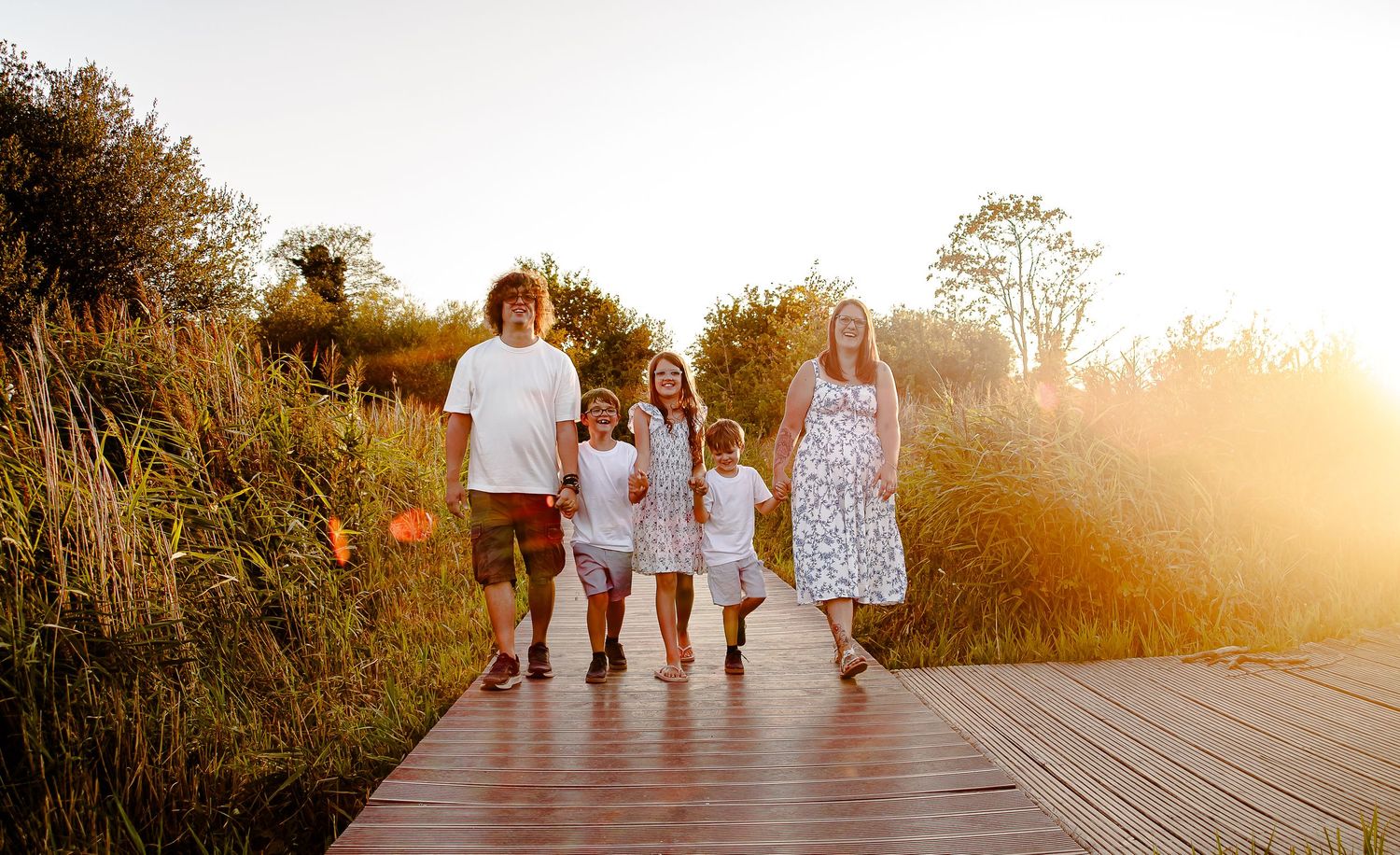 Family of five walking hand in hand at golden hour in Cosmeston Lakes