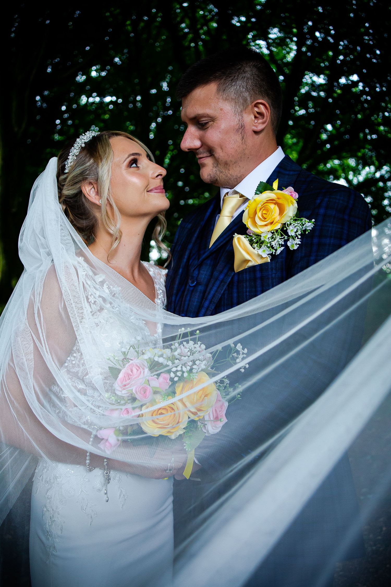 Newlyweds smiling at each other beneath the bride’s flowing veil at Ridgeway Golf Club