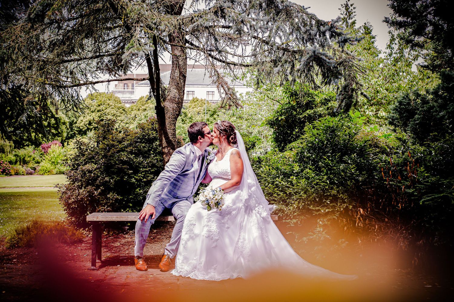 Bride and groom seated together on a garden bench