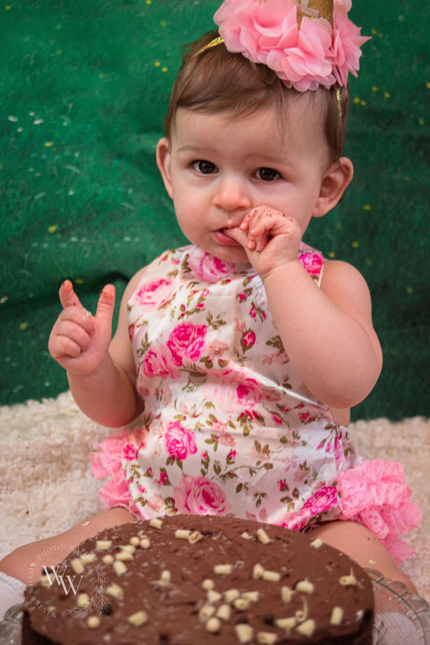 Baby girl enjoying a mouthful of cake during her first-birthday photoshoot