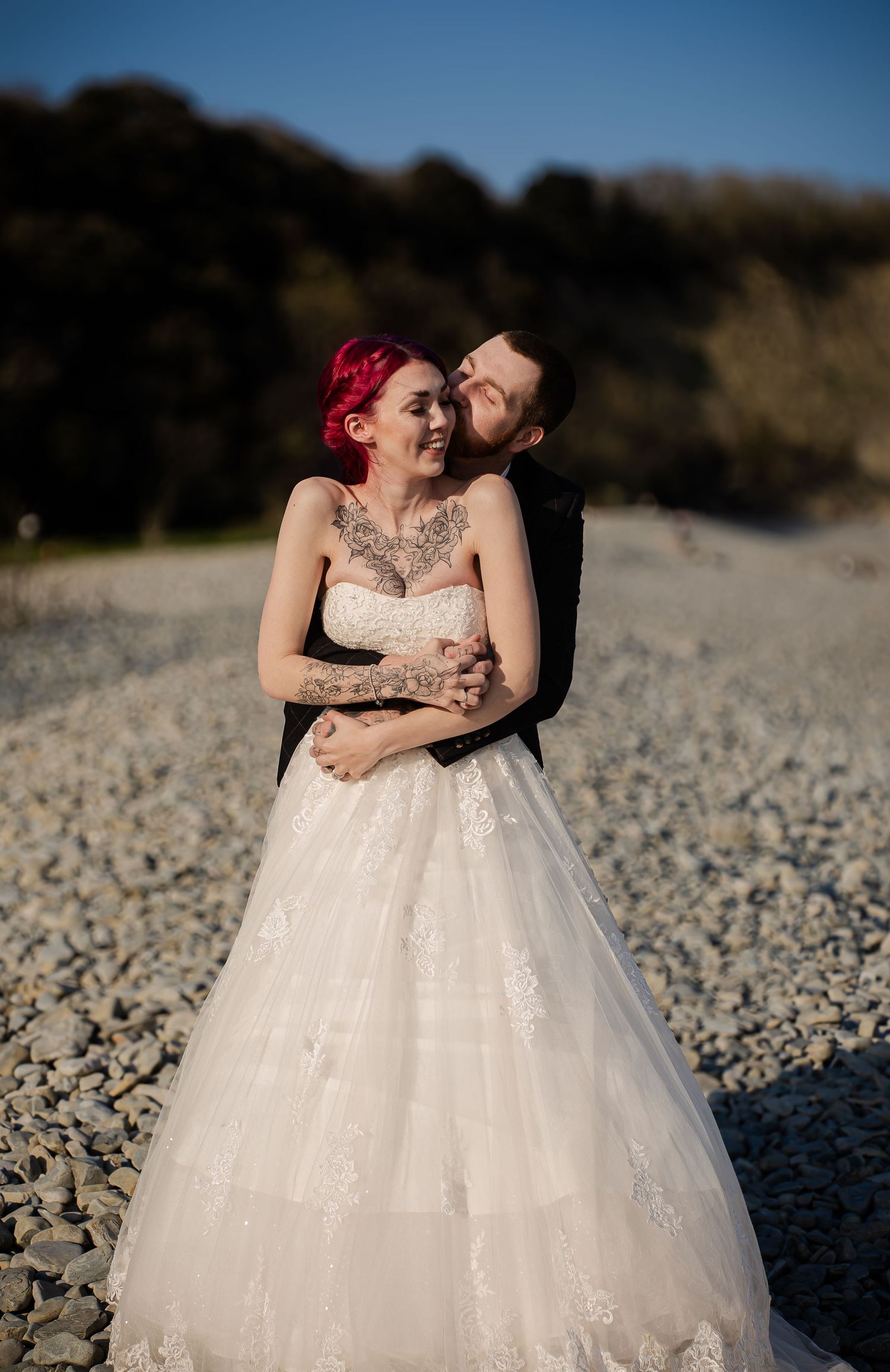 Groom embracing the bride from behind during their beach portraits