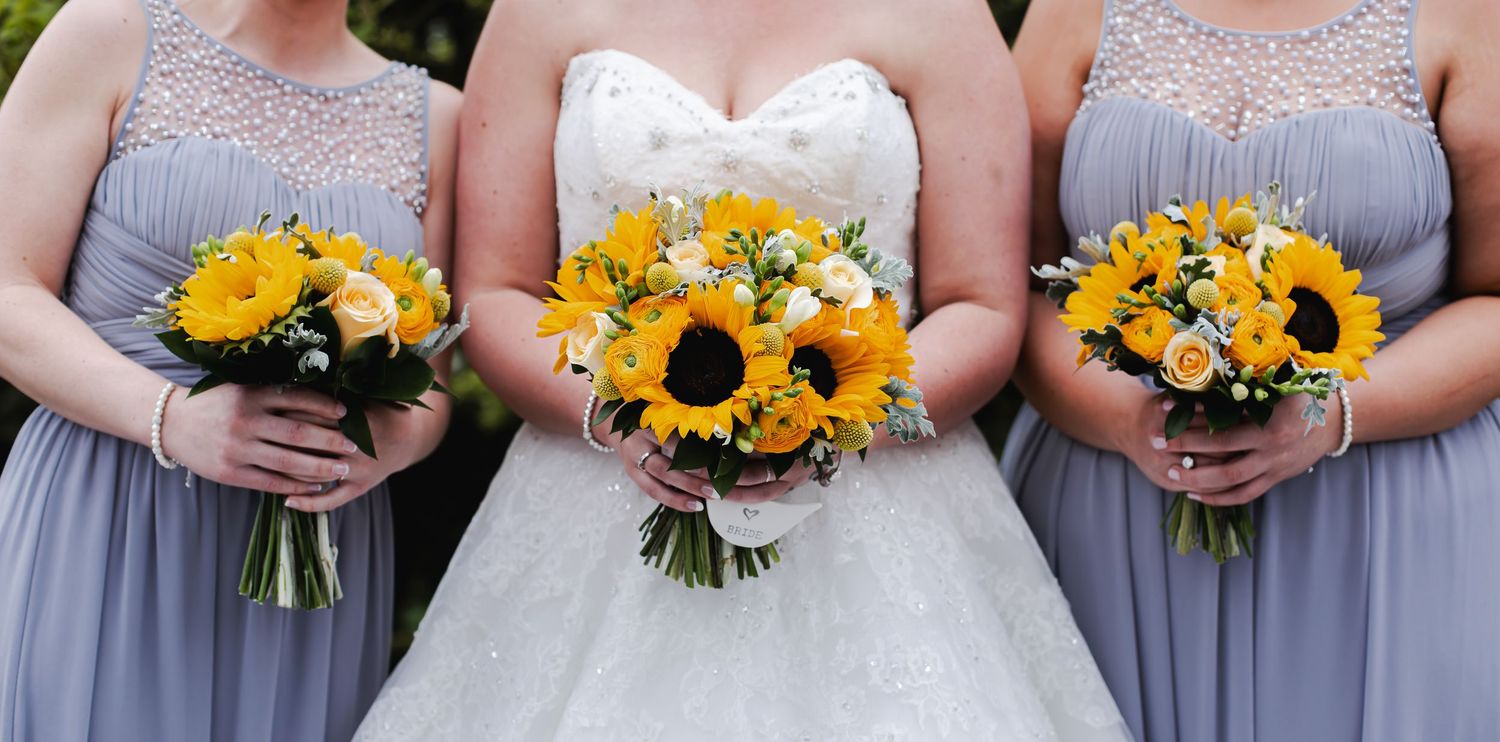 Bride with her bridesmaids while holding bright sunflower wedding bouquets