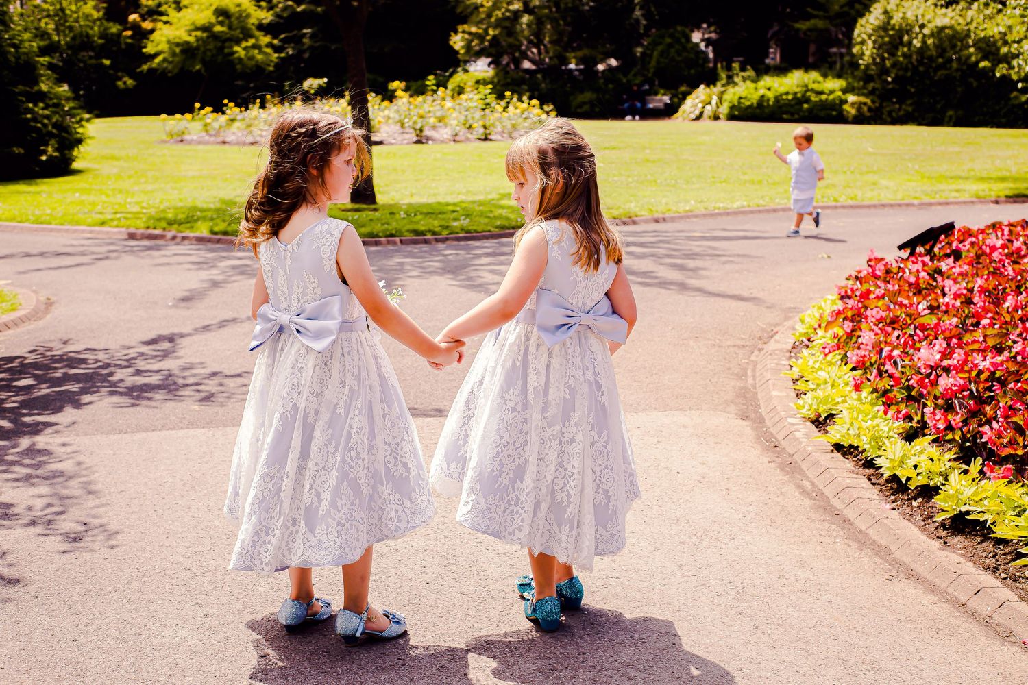 Two flower girls walking hand in hand through Sophia Gardens, Cardiff