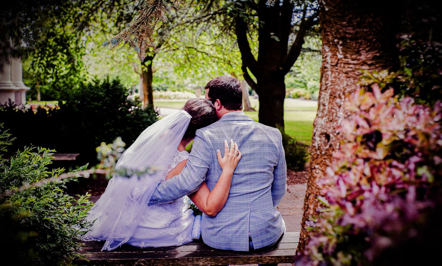 Newlyweds sitting closely together on a garden bench