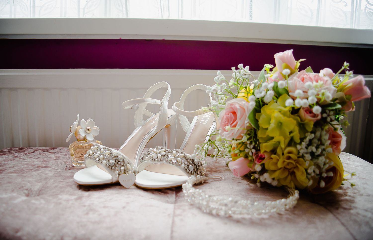 Bridal shoes, jewellery and colourful bouquet arranged before the wedding