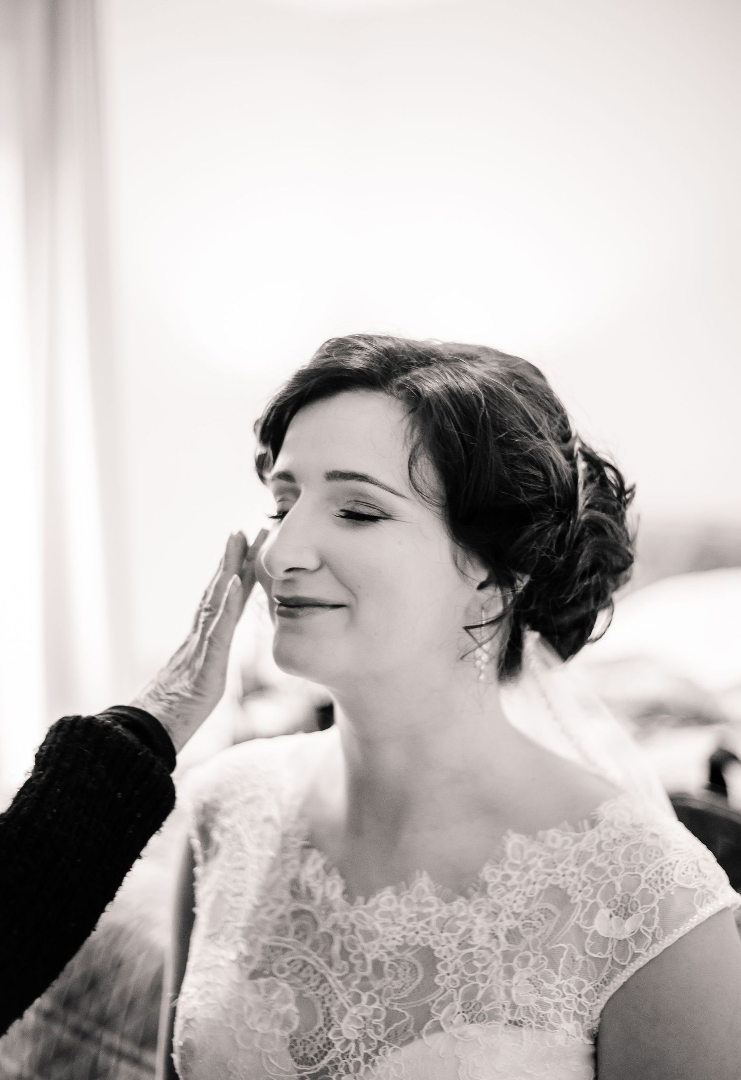 Black-and-white portrait of the bride having her makeup applied