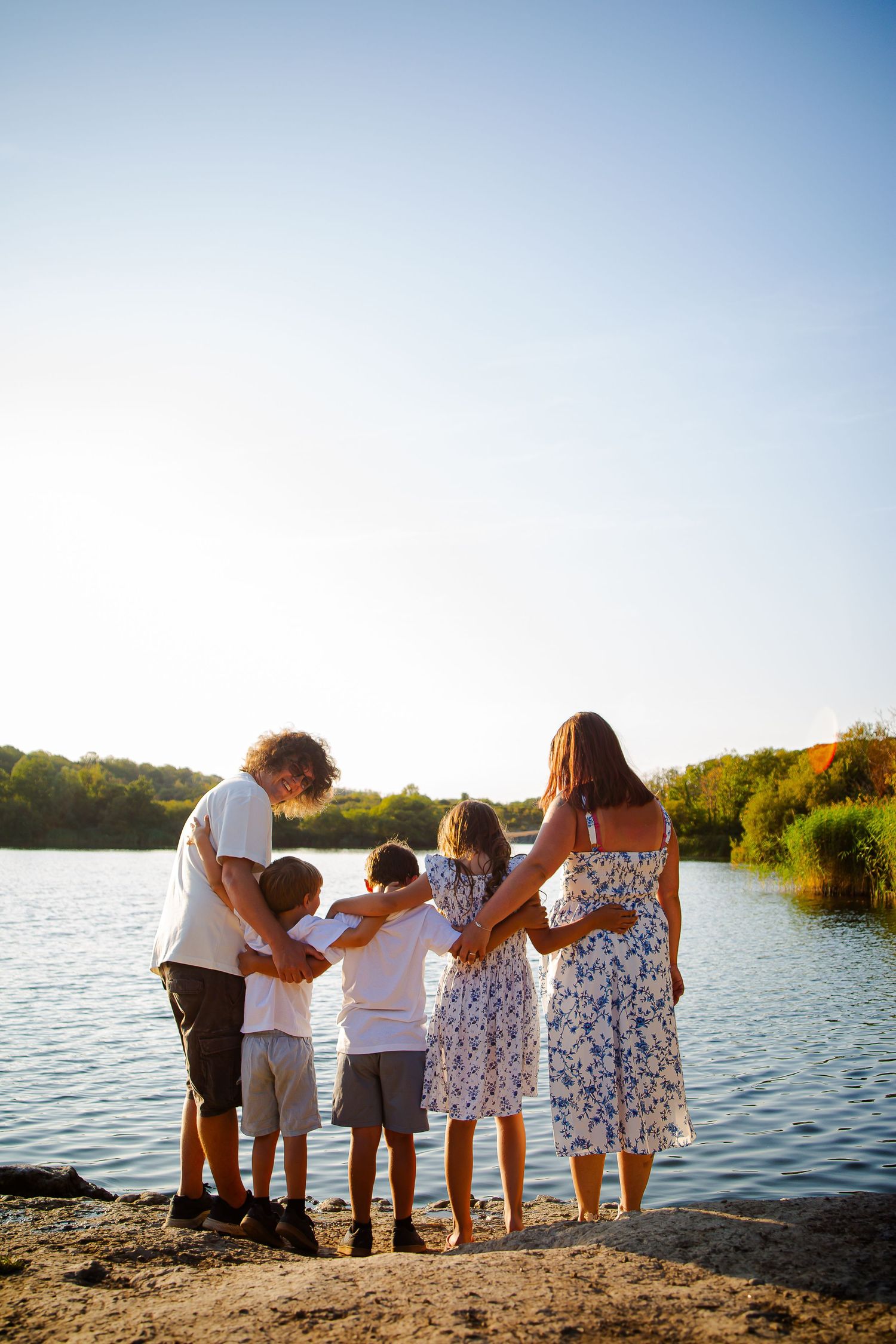 Family standing in a circle and holding hands beside Cosmeston Lake