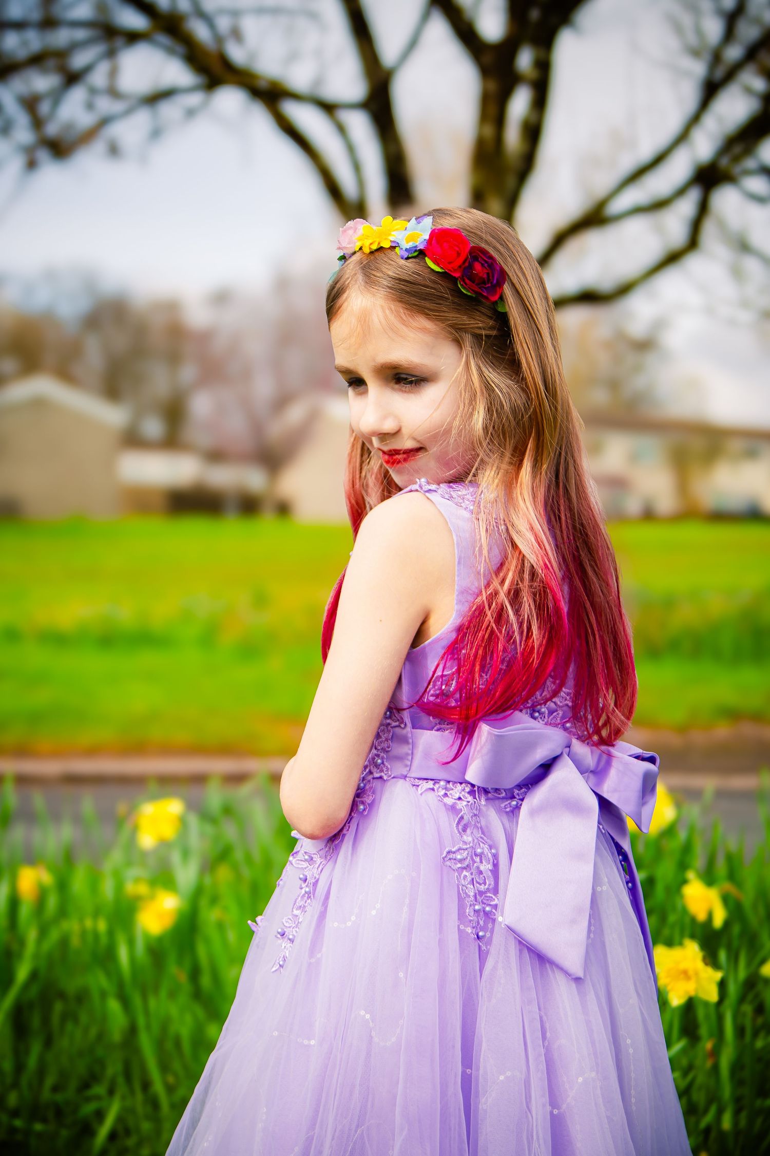 Young girl in a purple dress looking back among the daffodils