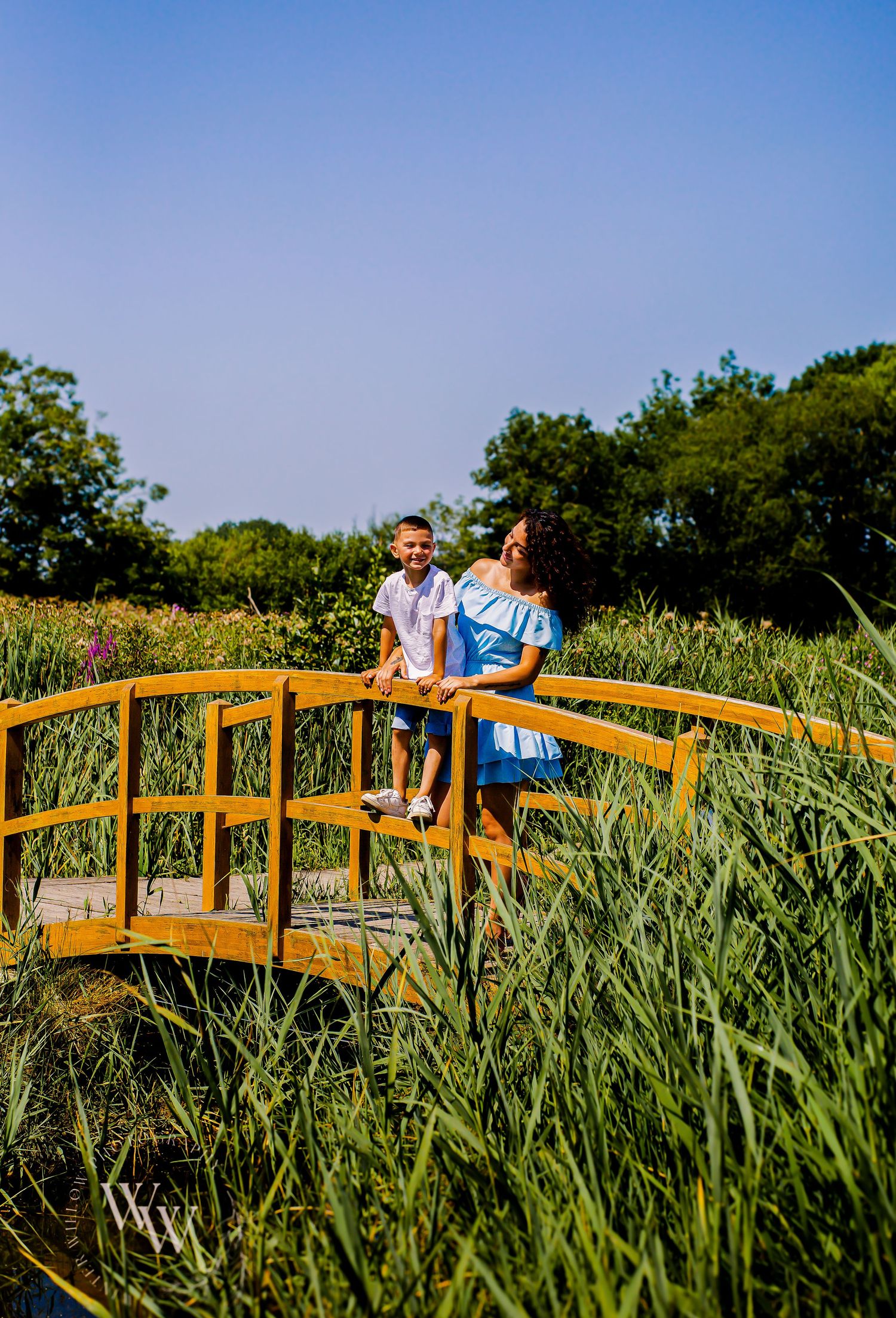 Mother and children posing on a wooden bridge surrounded by reeds at Cosmeston Lake, Penarth