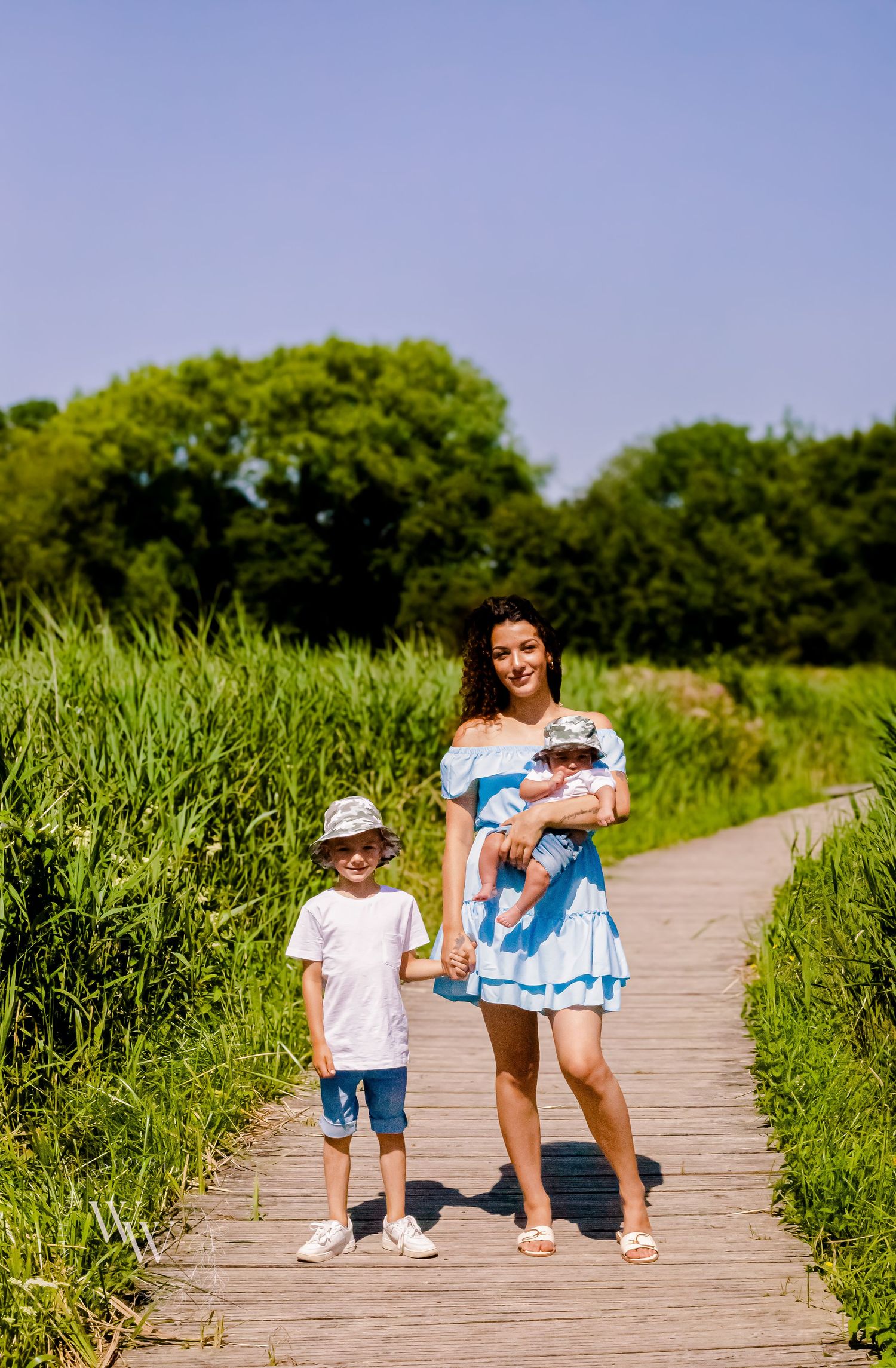 Mother standing with her two children on a summer boardwalk at Cosmeston Lake, Penarth
