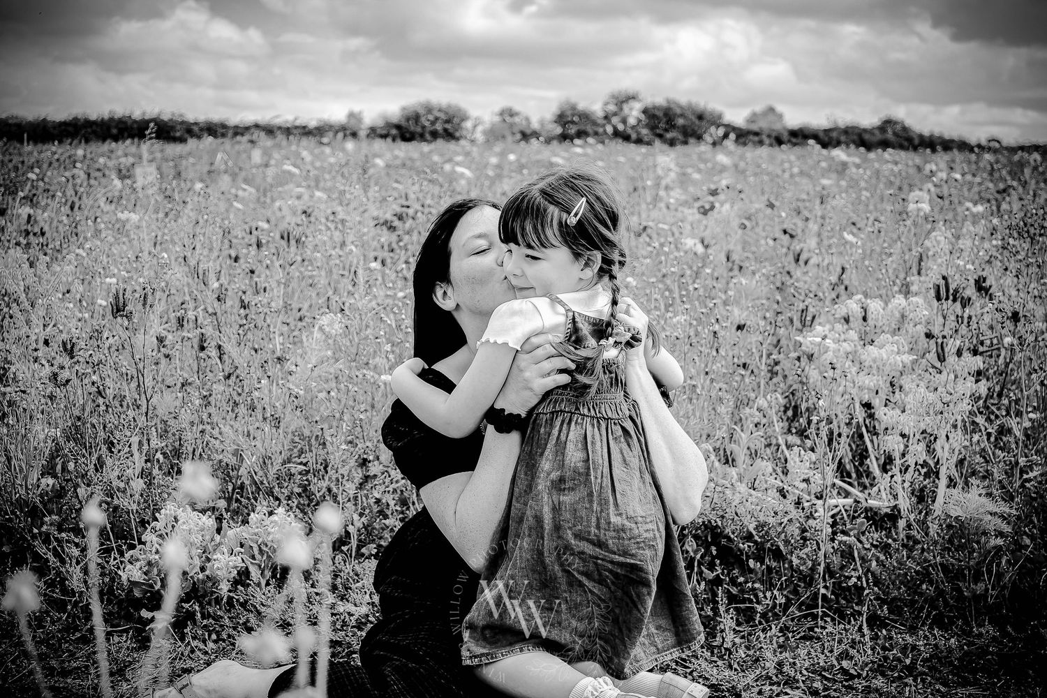 Black and white photograph of a mother embracing her daughter in a flower field