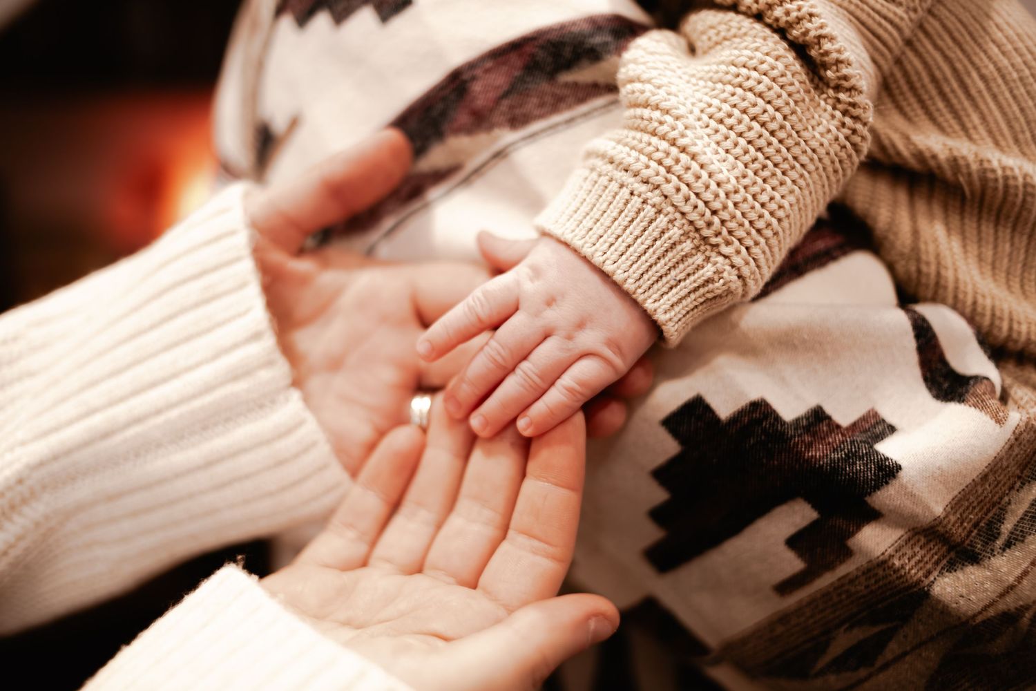 Newborn baby’s hand resting against a parent’s palm