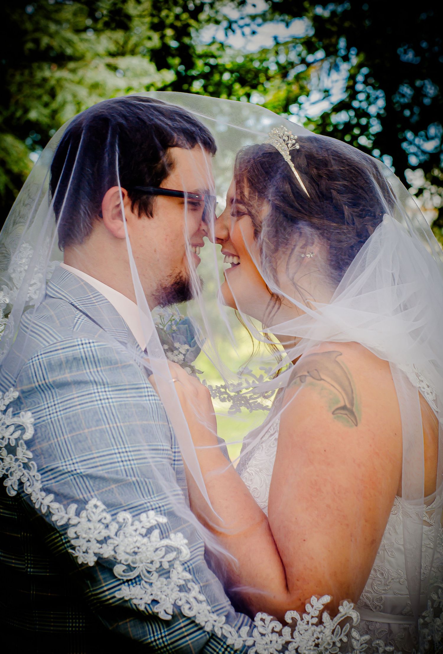 Newlyweds touching foreheads beneath the bride’s lace veil