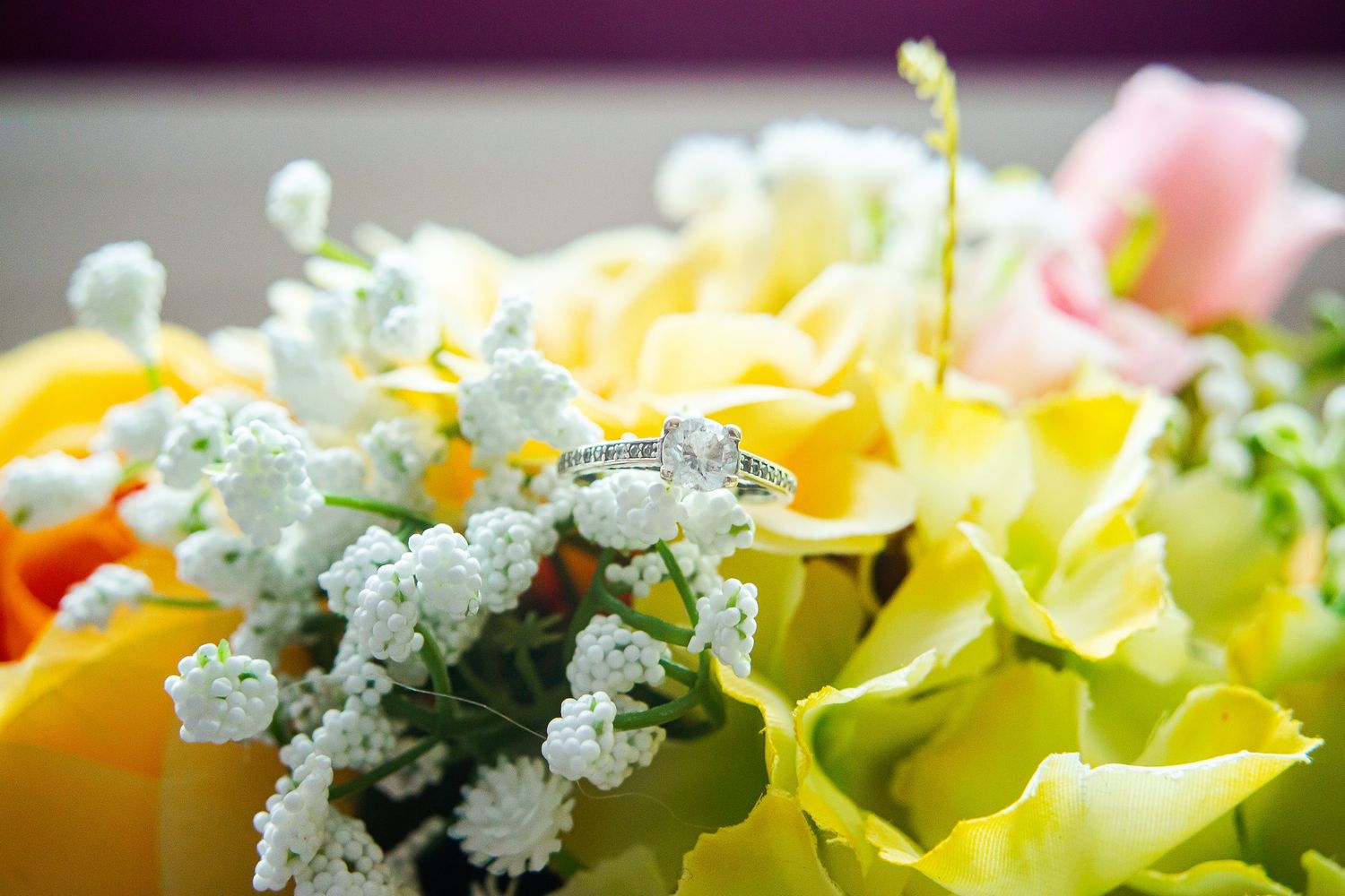 Close-up of a colourful bridal bouquet with yellow and pink flowers with wedding ring