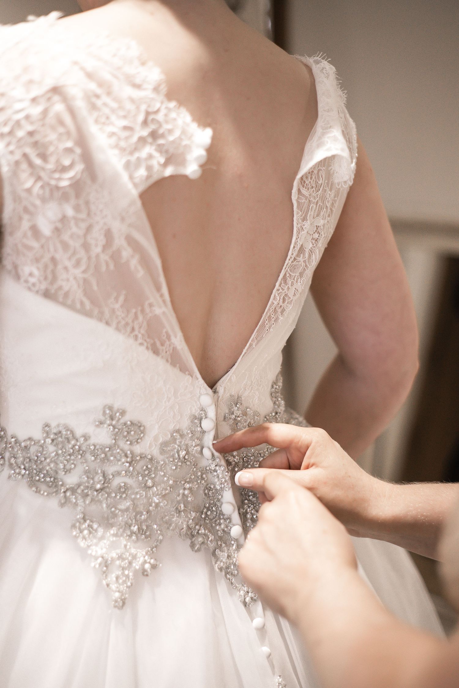Close-up of a jewelled belt being fastened around the wedding dress