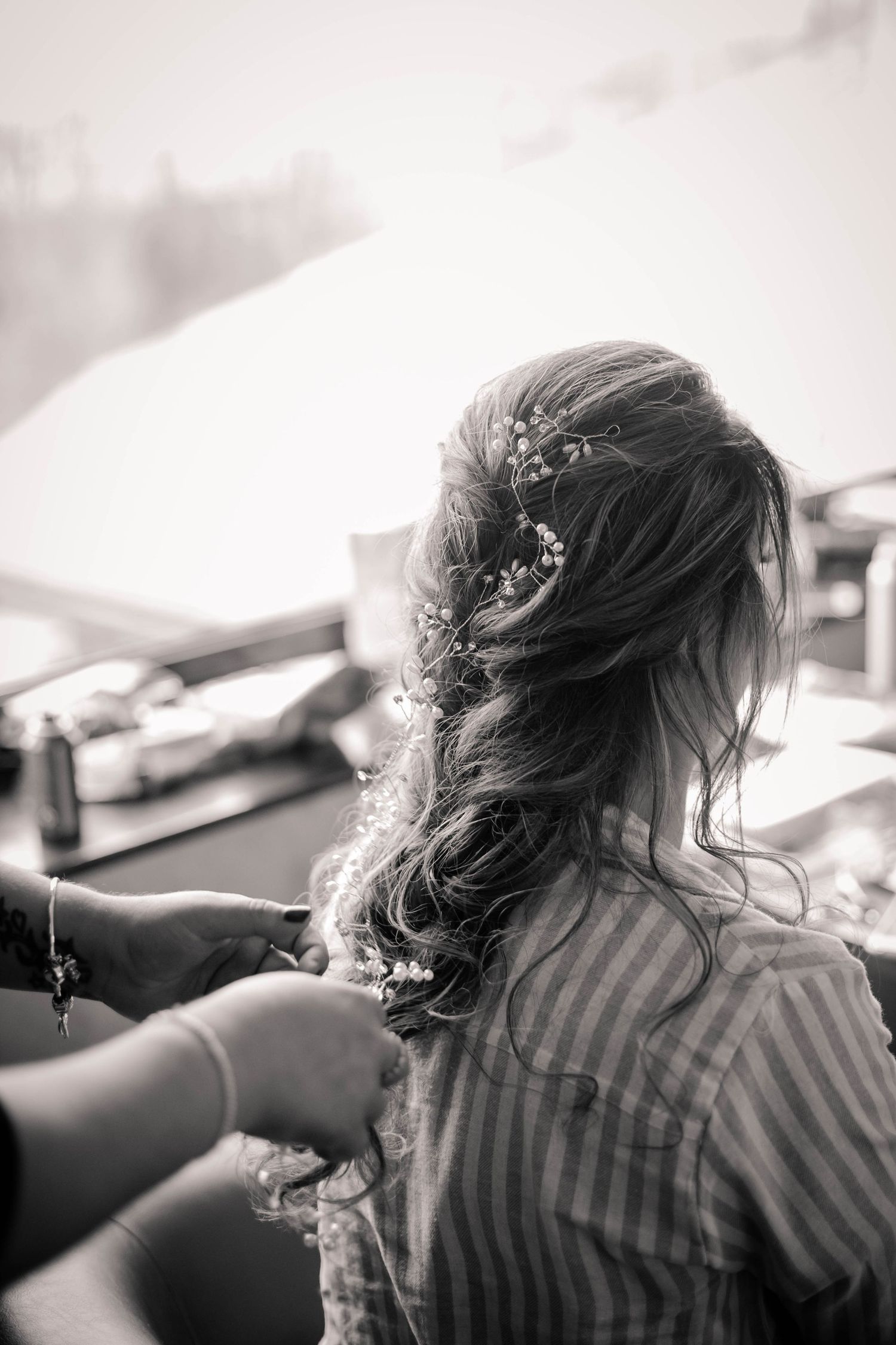 Black and white photograph of a bridesmaid having her hair styled
