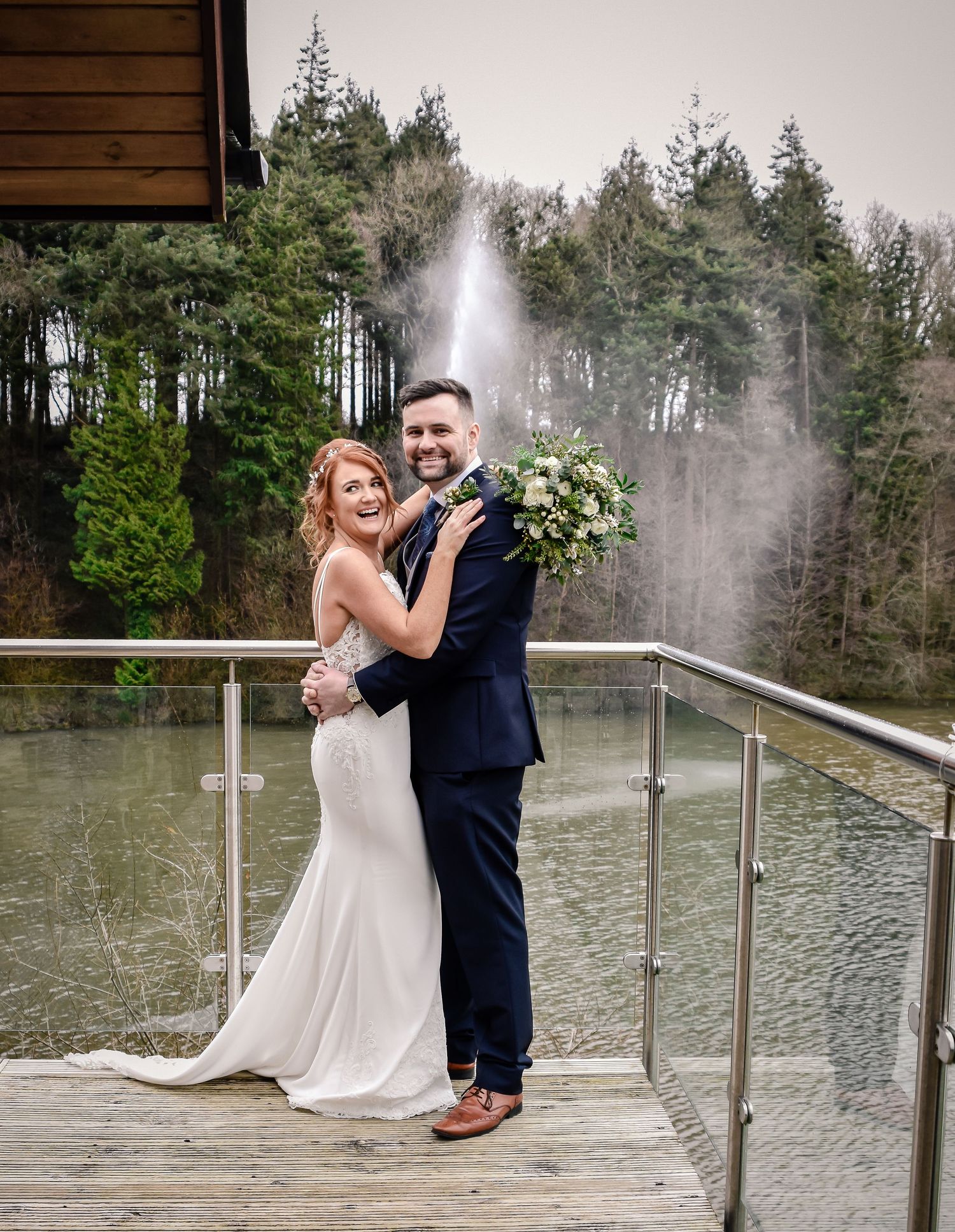 Bride and groom smiling together beside the lake at Canada Lodge in Cardiff
