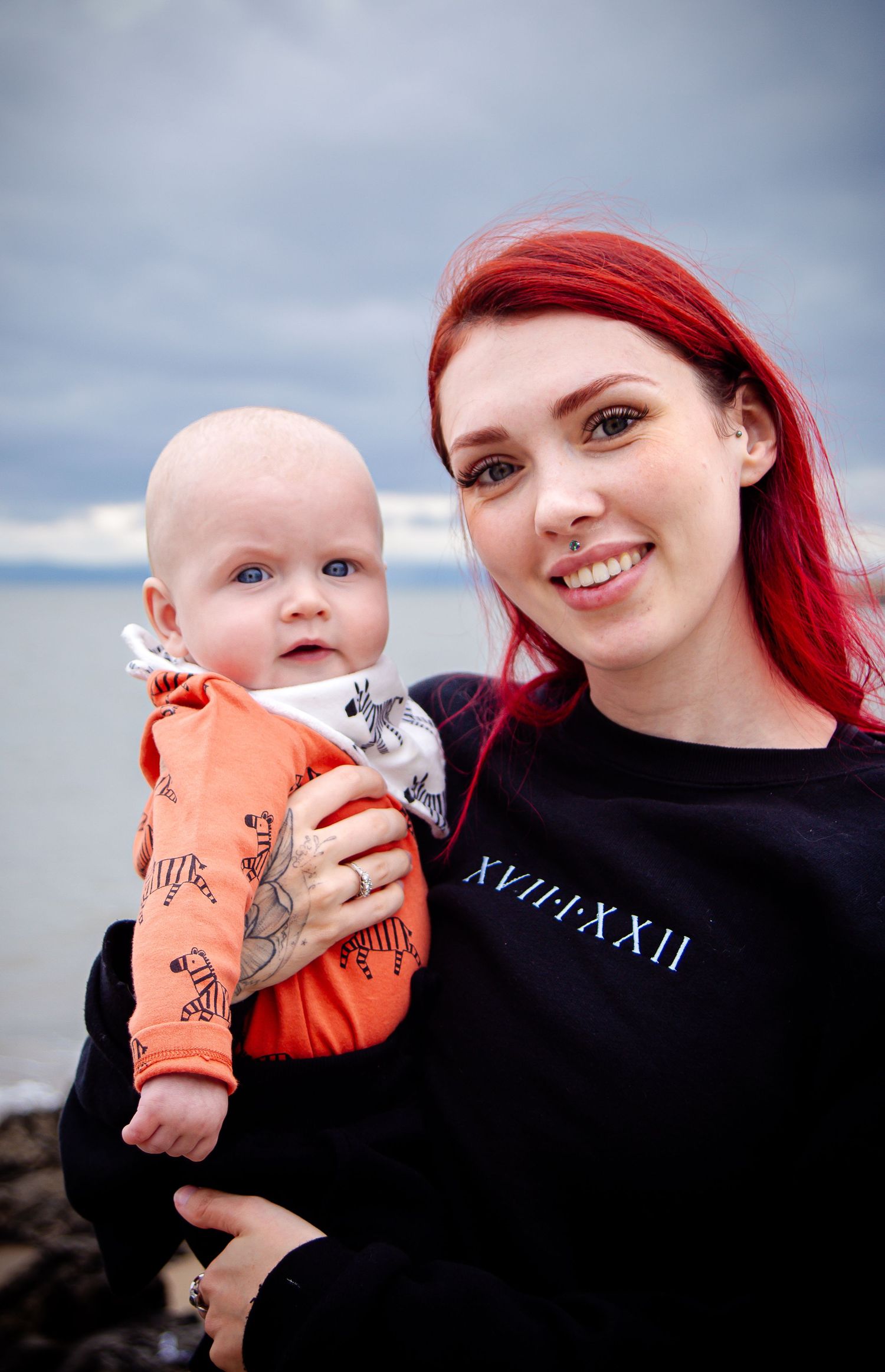 Red-haired mother holding her smiling baby at Barry Island