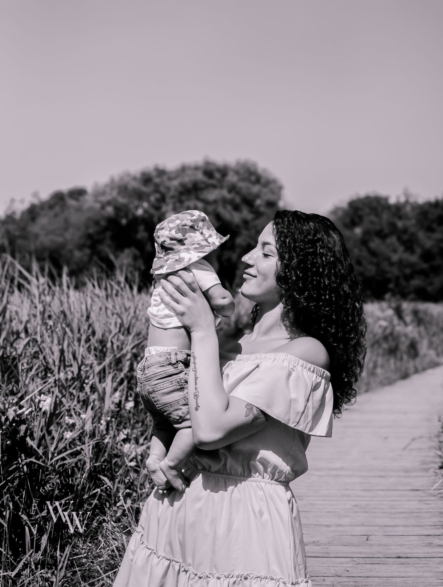 Black and white photograph of a mother lifting her baby affectionately at Cosmeston Lake, Penarth
